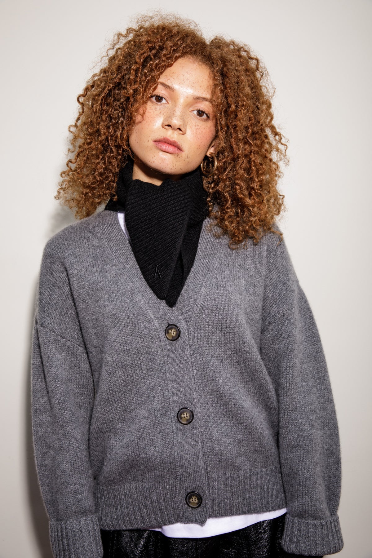 Knitted Cashmere Neck Tie in black styled over a grey V-neck cardigan, showing ribbed texture and K logo detail