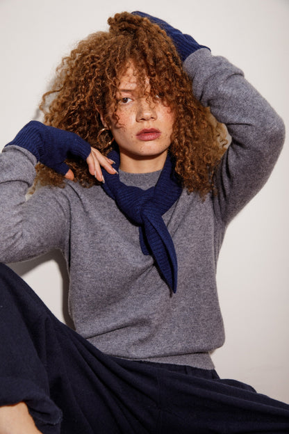 Knitted Cashmere Neck Tie in Cosmos navy blue, styled knotted at the neck over a grey cashmere sweater on a model