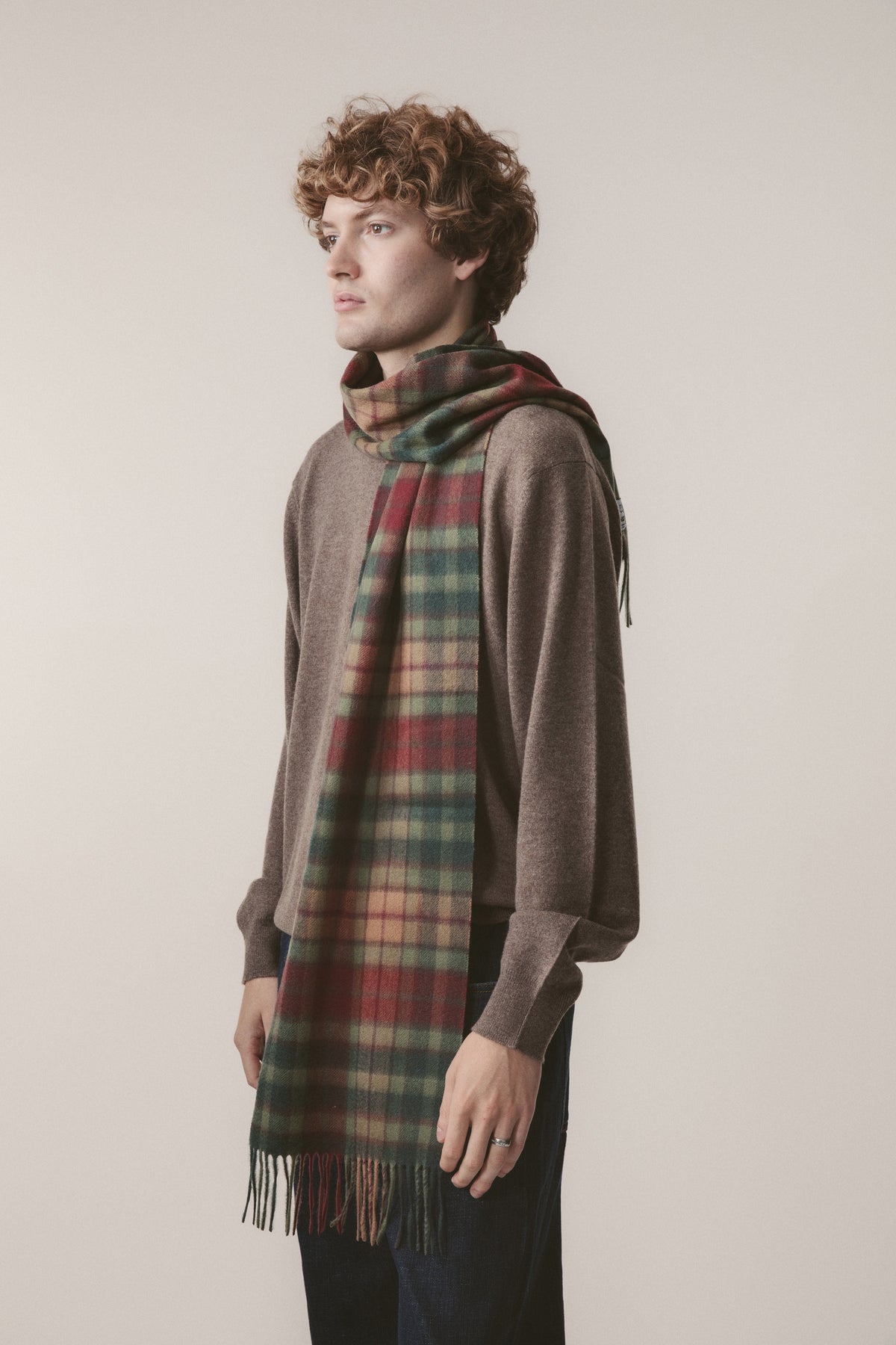 Heritage Tartan Cashmere Scarf in Autumn Buchanan worn draped over a sweater, featuring red, green, and gold plaid with fringe hem