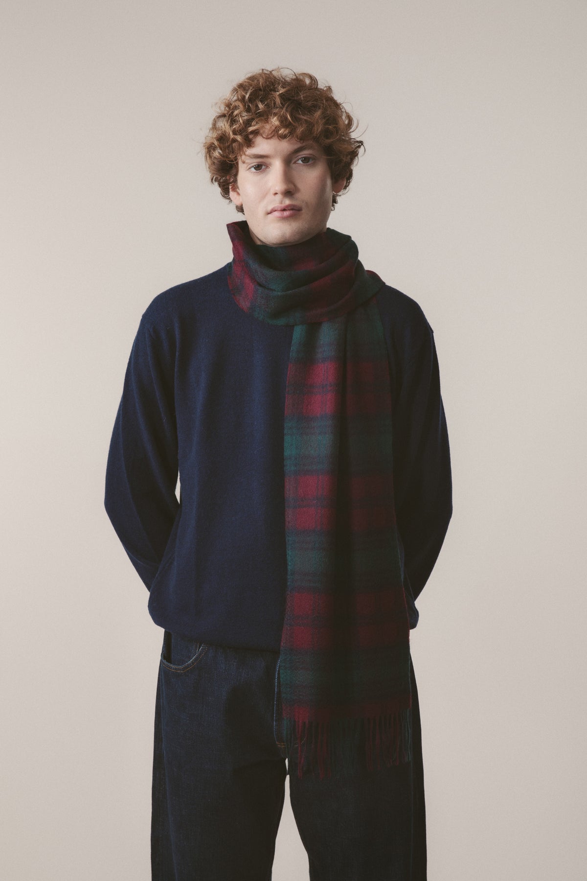 Heritage Tartan Cashmere Scarf in Lindsay tartan with teal, burgundy, and dark green plaid, worn draped over a navy sweater
