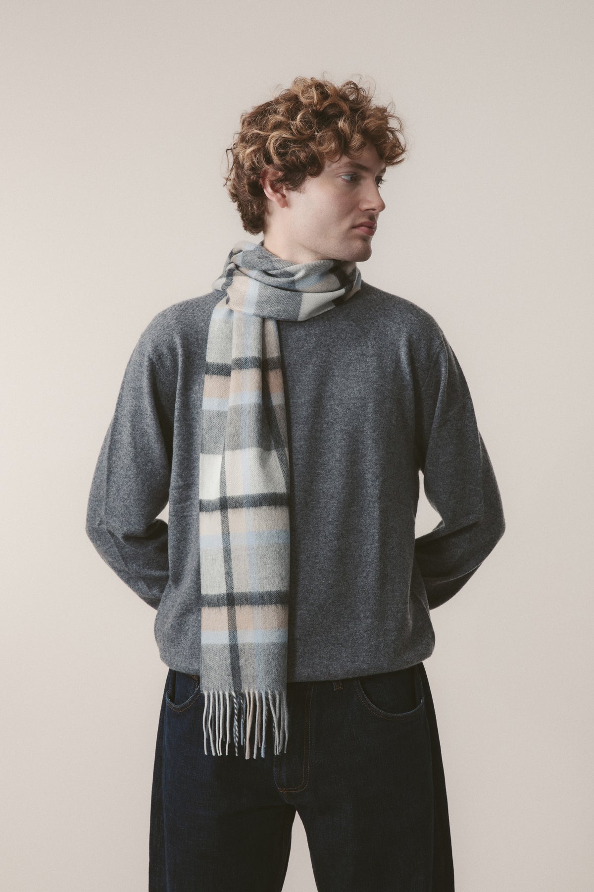 Princeton Check Cashmere Scarf in Blue worn loosely draped by a model, showing soft plaid pattern with blue, cream, and grey tones and fringed ends