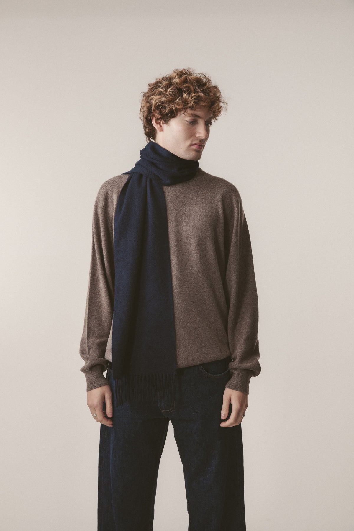 Solid Cashmere Scarf in Dark Navy with fringed ends, styled on a model over a brown knit sweater