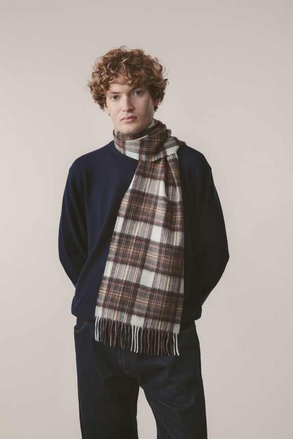 Heritage Tartan Cashmere Scarf in Natural Dress Stewart, brown and cream plaid with fringed ends, worn draped over a navy sweater