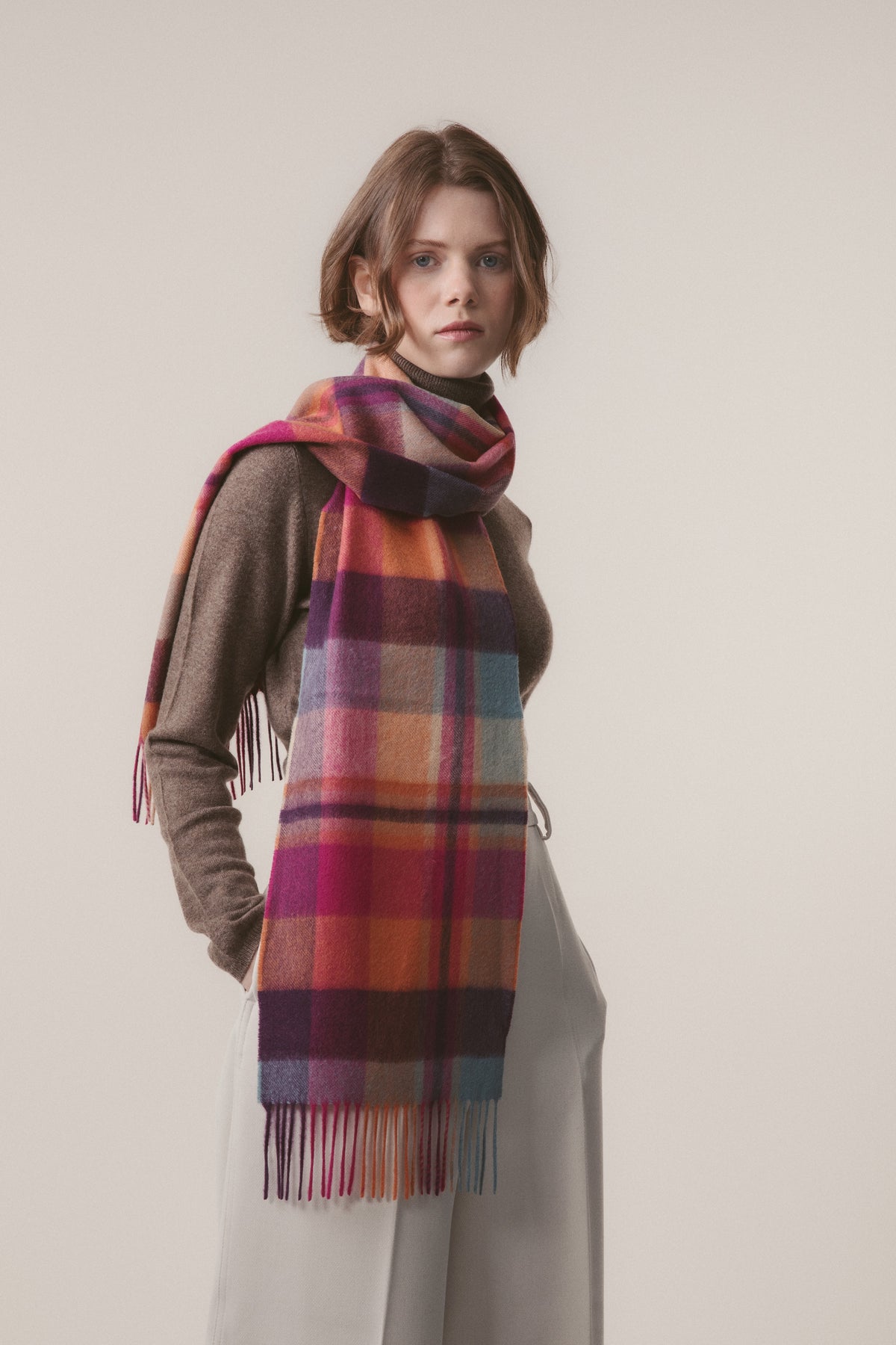 Model wearing Square Check Cashmere Scarf - Orient Ginger draped over one shoulder, showing full plaid pattern with fringed ends
