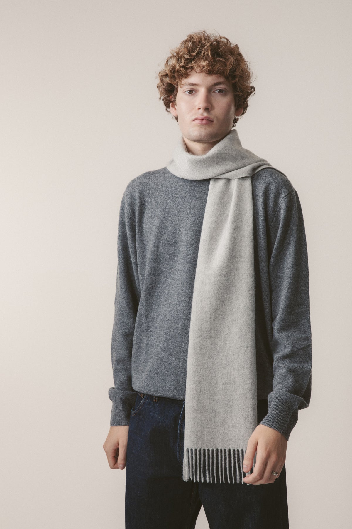 Solid Cashmere Scarf in Oyster Grey with fringed ends, worn draped over a charcoal sweater by a male model