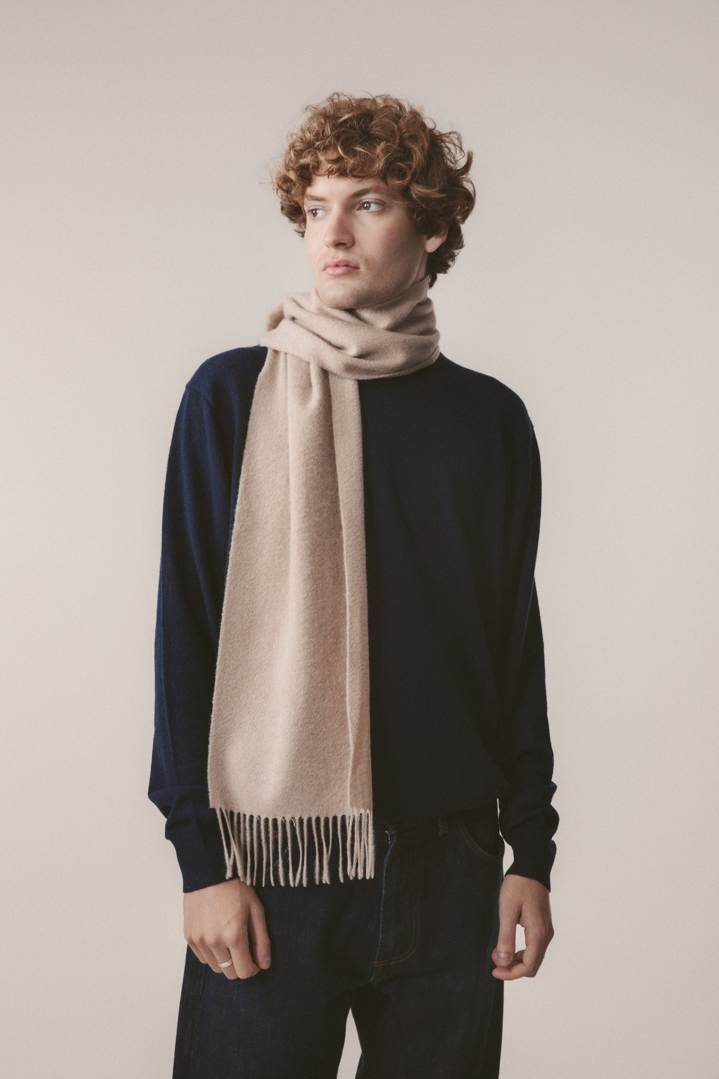 Solid Cashmere Scarf in Vicuna worn loosely wrapped around the neck, showing soft beige tone and fringed ends