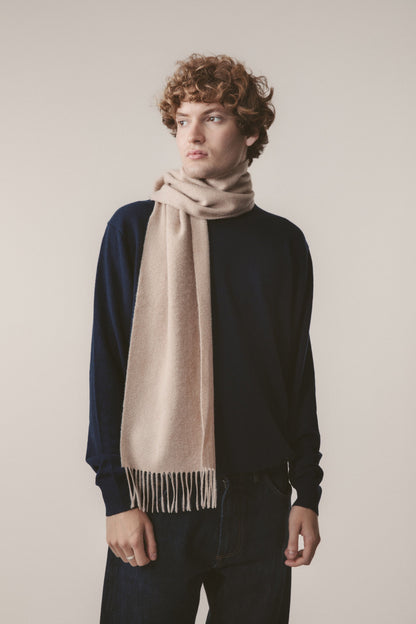 Solid Cashmere Scarf in Vicuna worn loosely wrapped around the neck, showing soft beige tone and fringed ends