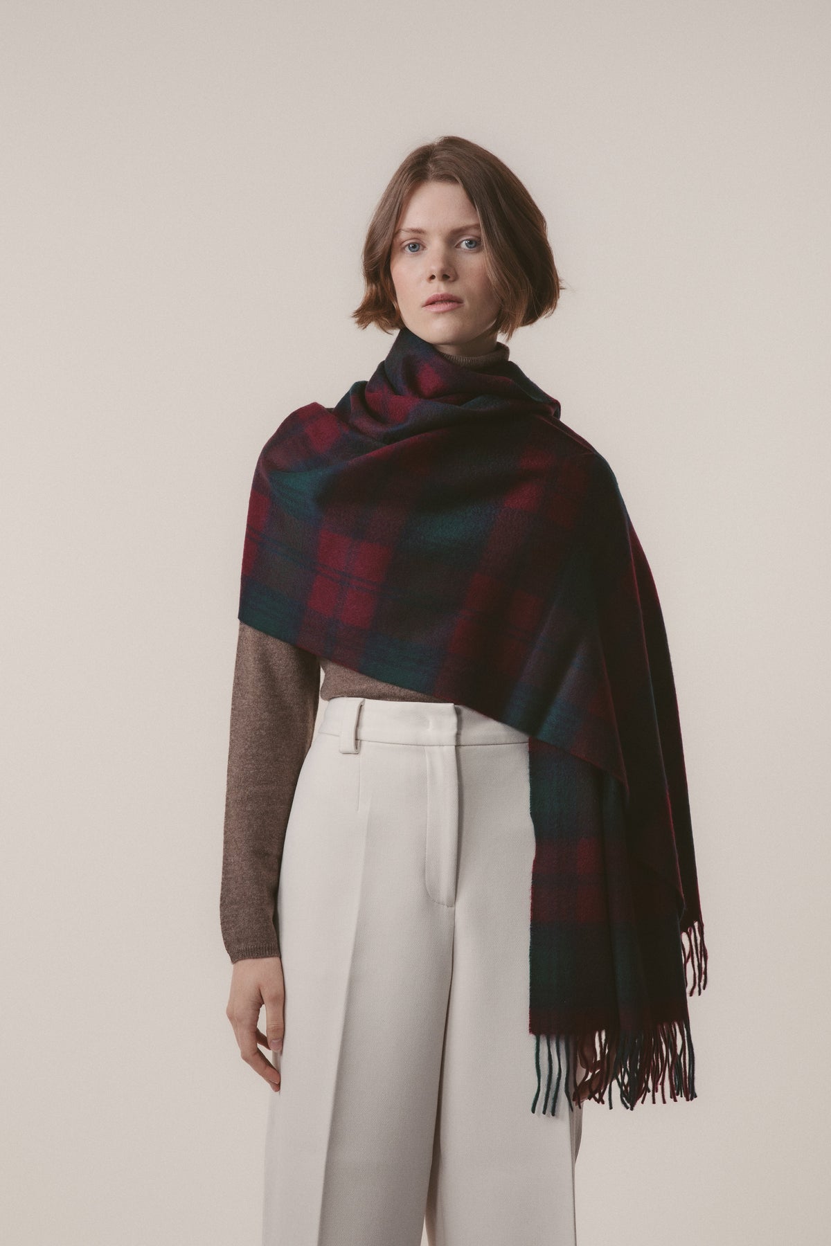 Heritage Tartan Cashmere Stole - Lindsay draped over one shoulder, showing the deep red and green tartan pattern with fringed ends