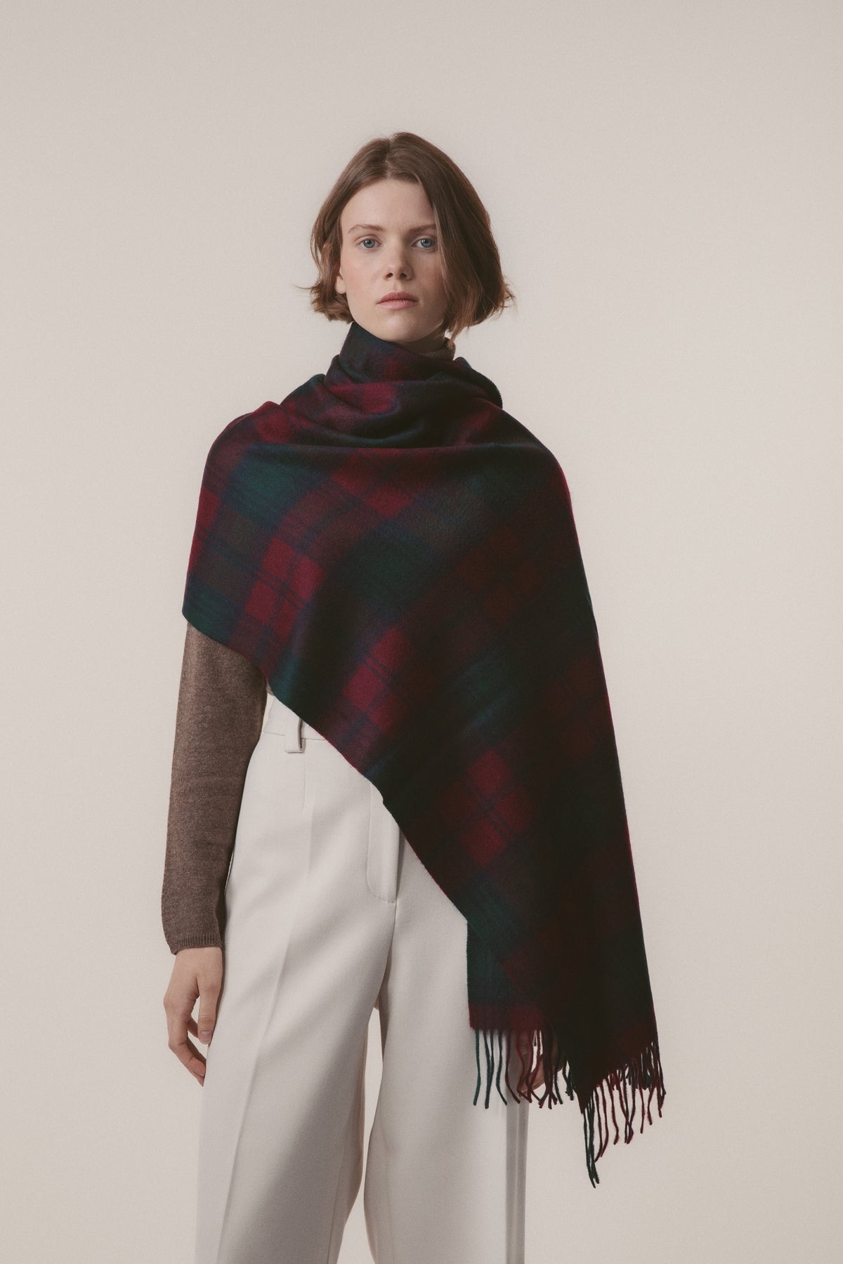 Heritage Tartan Cashmere Stole - Lindsay draped over one shoulder showing full tartan pattern in deep red and green with fringe detail