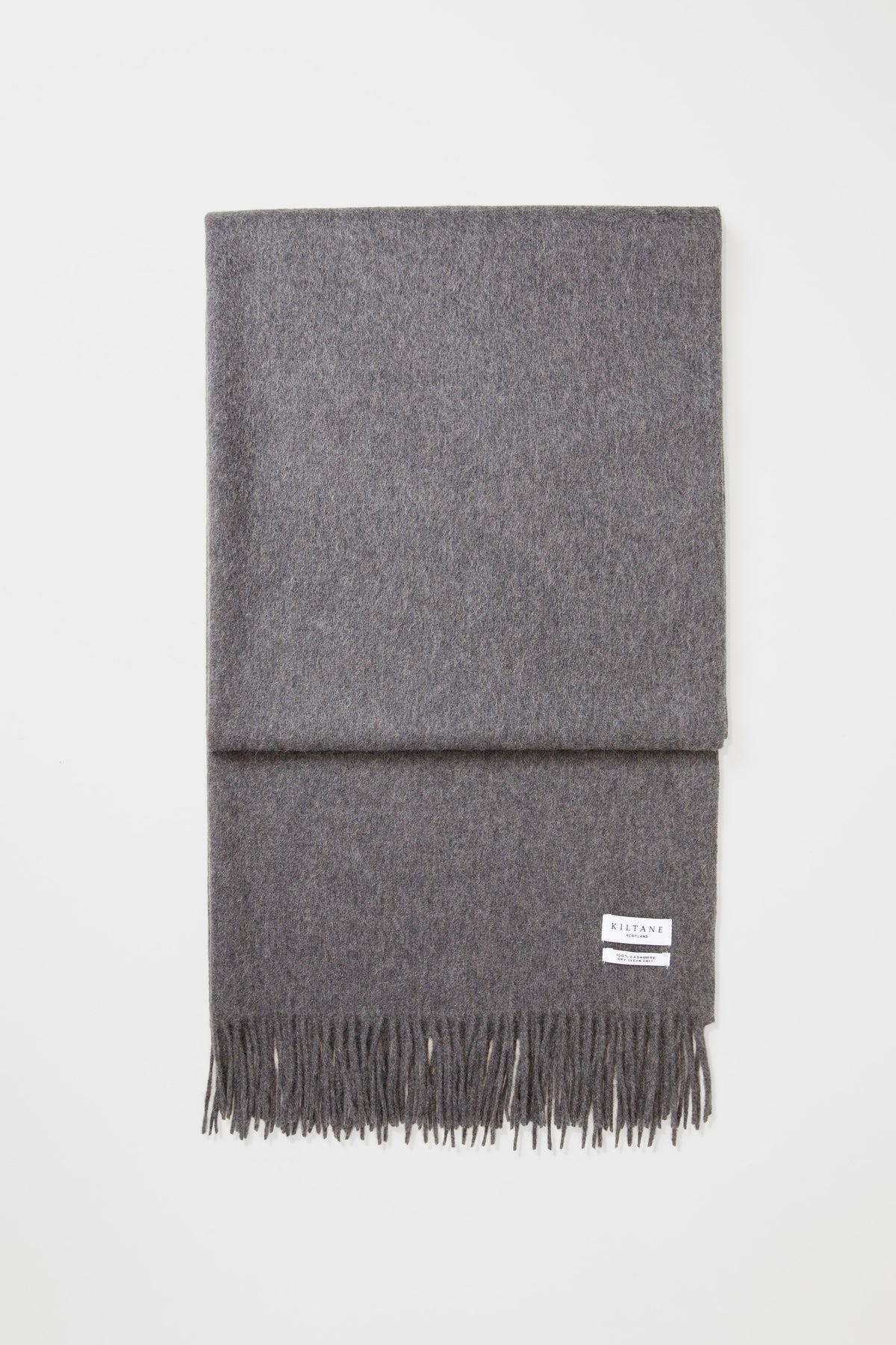 Kiltane Solid Cashmere Stole in Steinway Grey neatly folded flat, showing the brand label and fringed edge detail