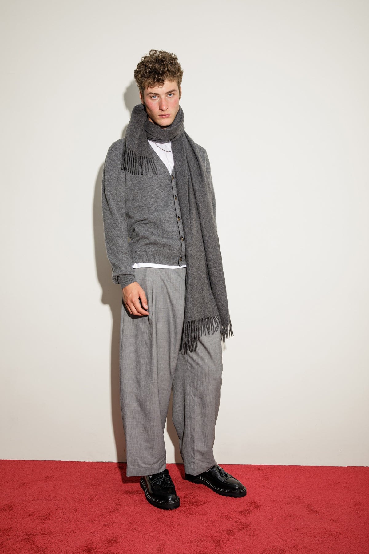 Solid Cashmere Stole in Steinway Grey styled as a scarf with fringed ends, worn over a grey cardigan and tailored trousers