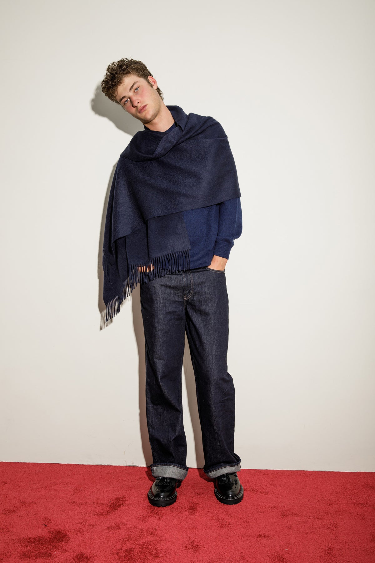 Solid Cashmere Stole in Dark Navy draped over one shoulder with fringed edge visible, styled with a navy sweater and jeans