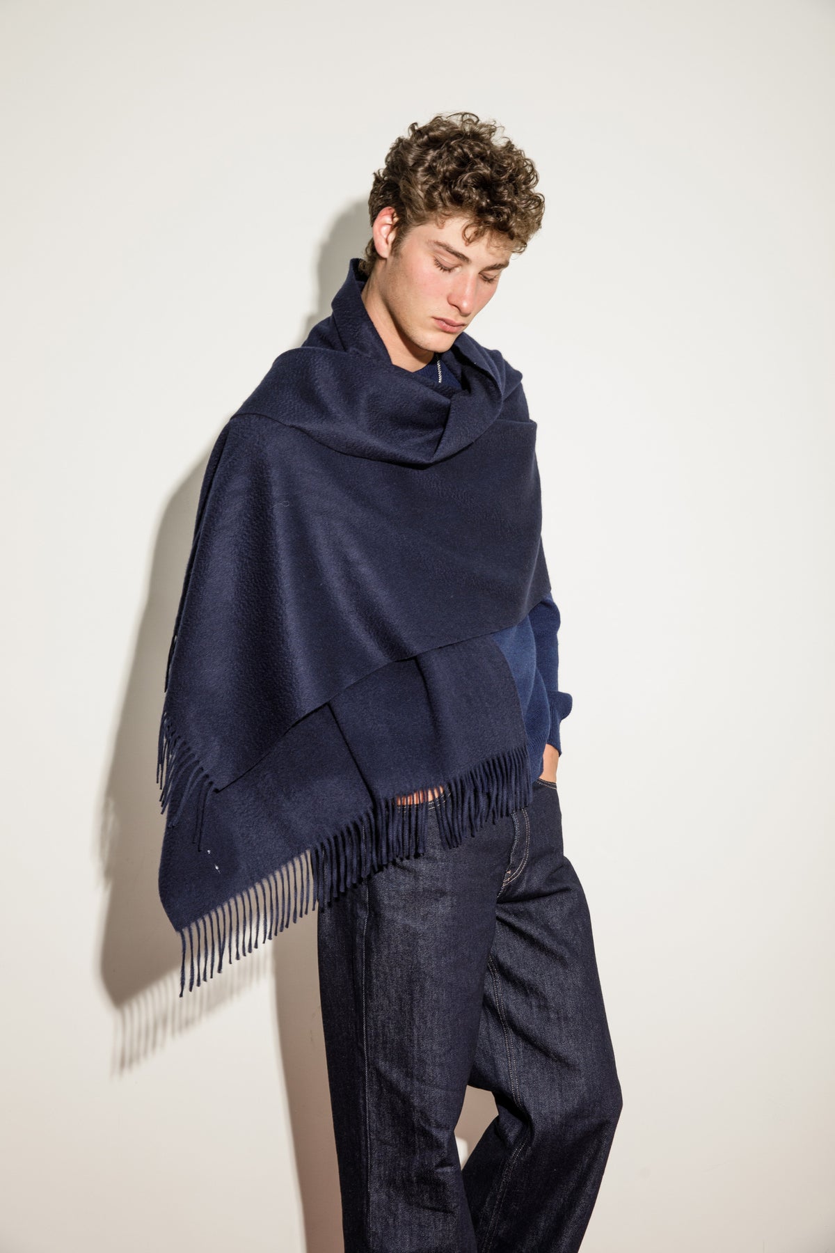 Model wearing the Solid Cashmere Stole in Dark Navy draped over shoulders, showing the soft texture and fringed hem detail