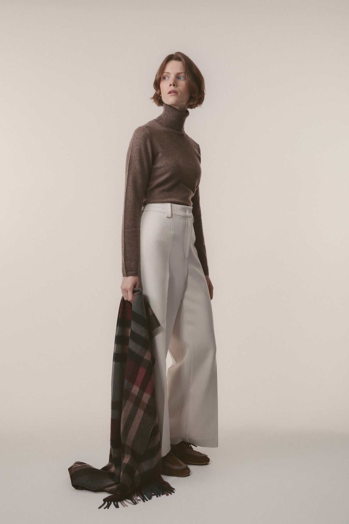 Tartan 2 Cashmere Stole in Burgundy Rust held casually at side, showing plaid pattern with fringed edge detail
