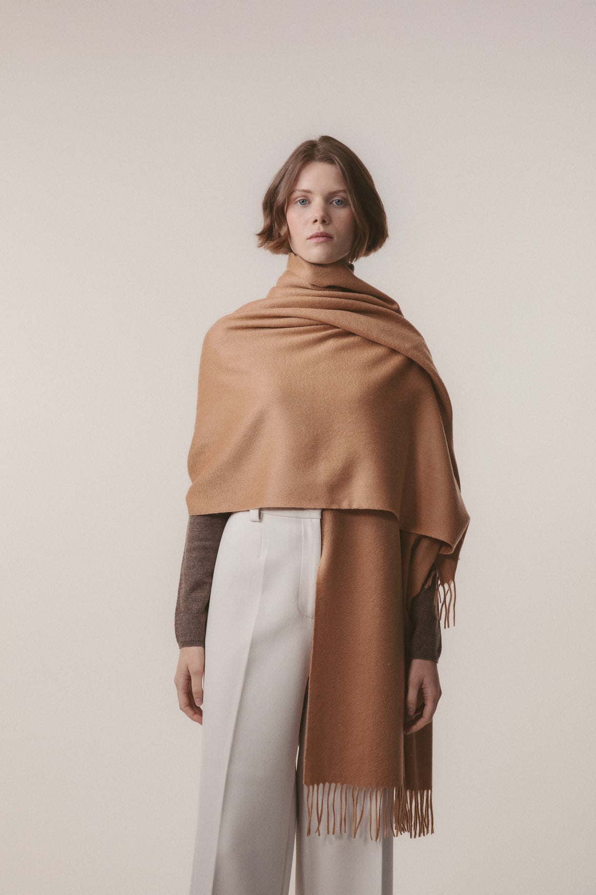 Solid Cashmere Stole in Dark Camel draped over shoulders, showing soft brushed texture and fringed ends