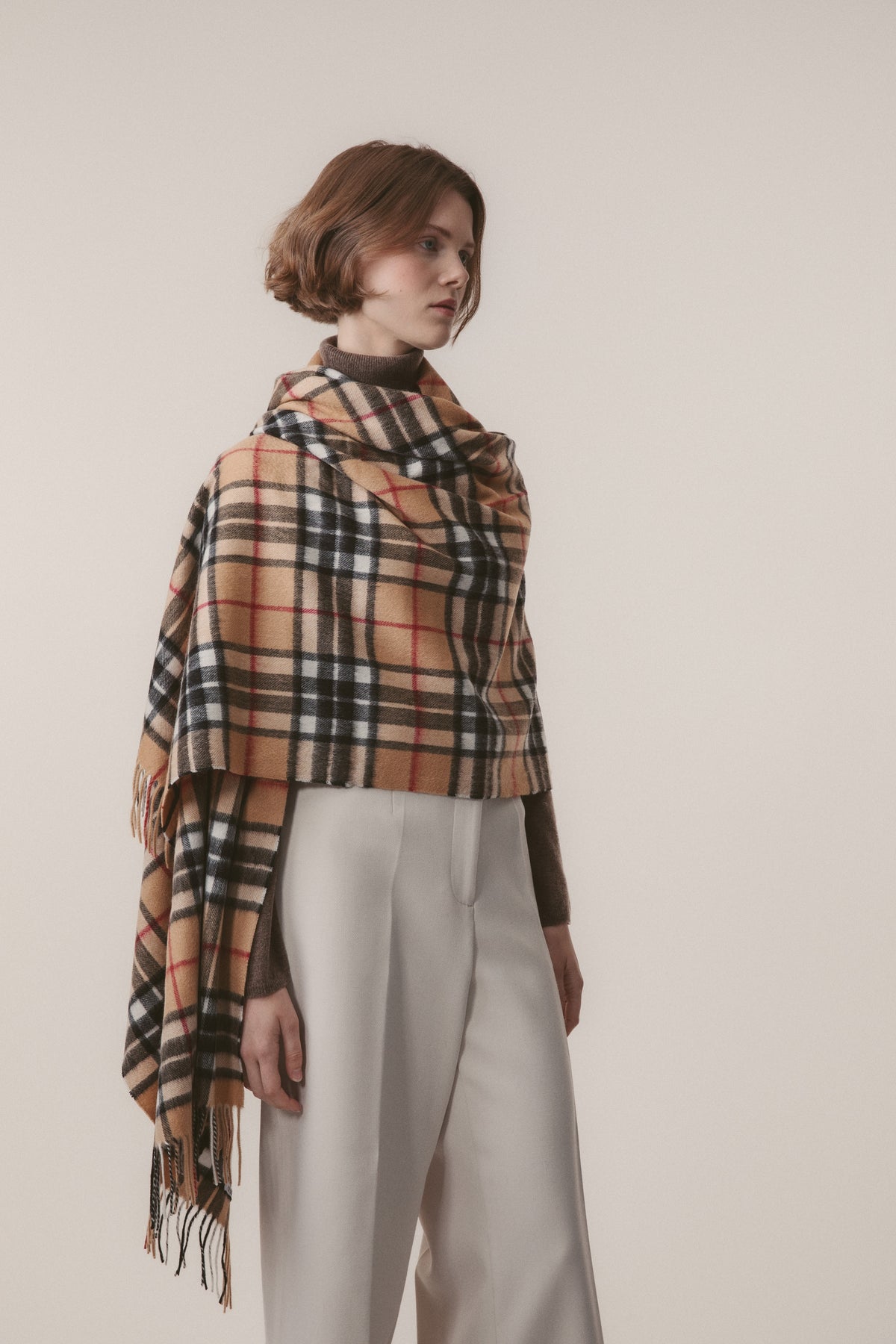 Scotty Thompson Cashmere Stole in Camel, a classic tartan plaid in camel, black, white, and red, draped as a wrap with fringed edges