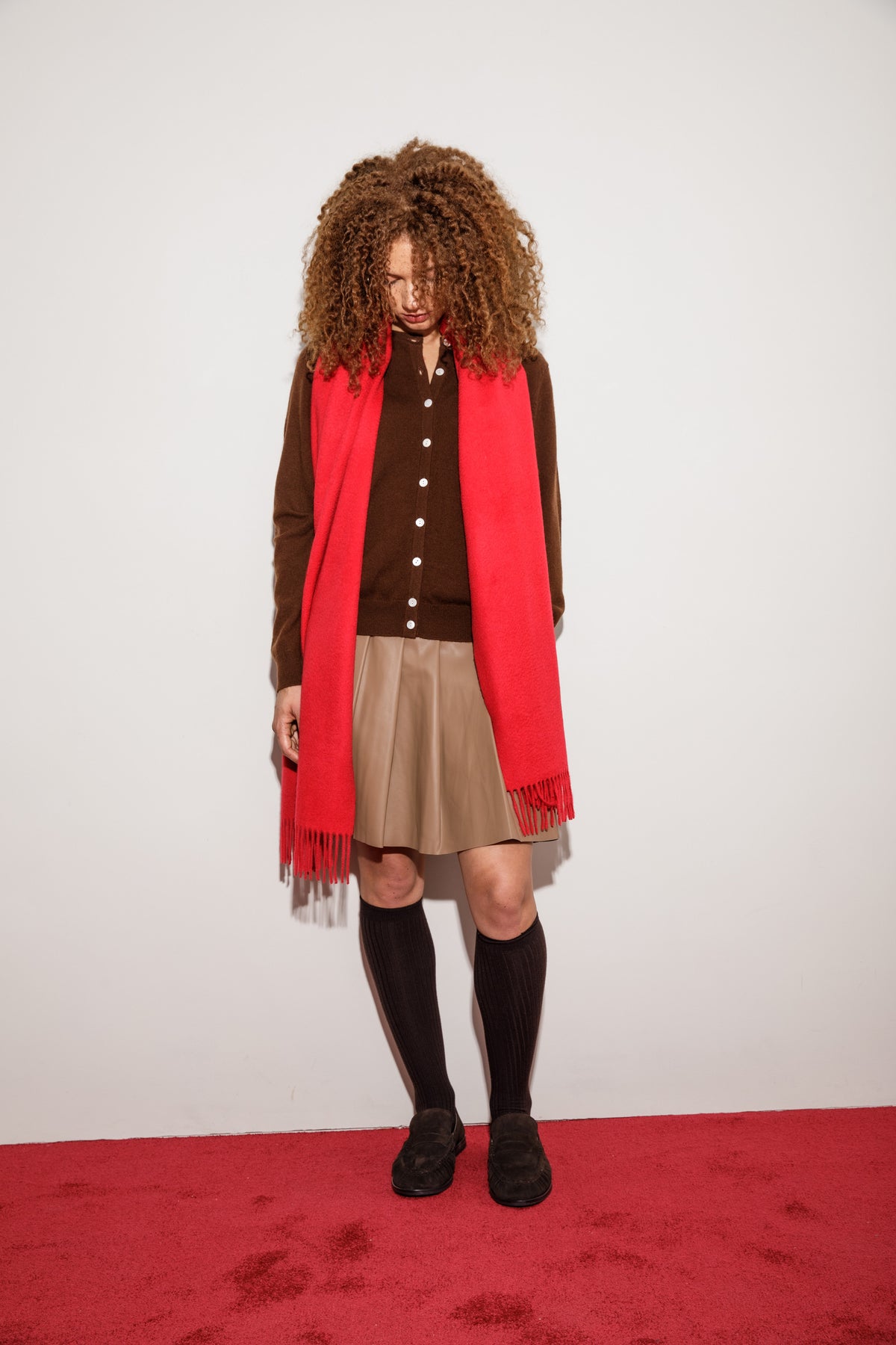 Solid Cashmere Wide Scarf in Red styled draped over shoulders with fringed ends visible, paired with brown cardigan and skirt