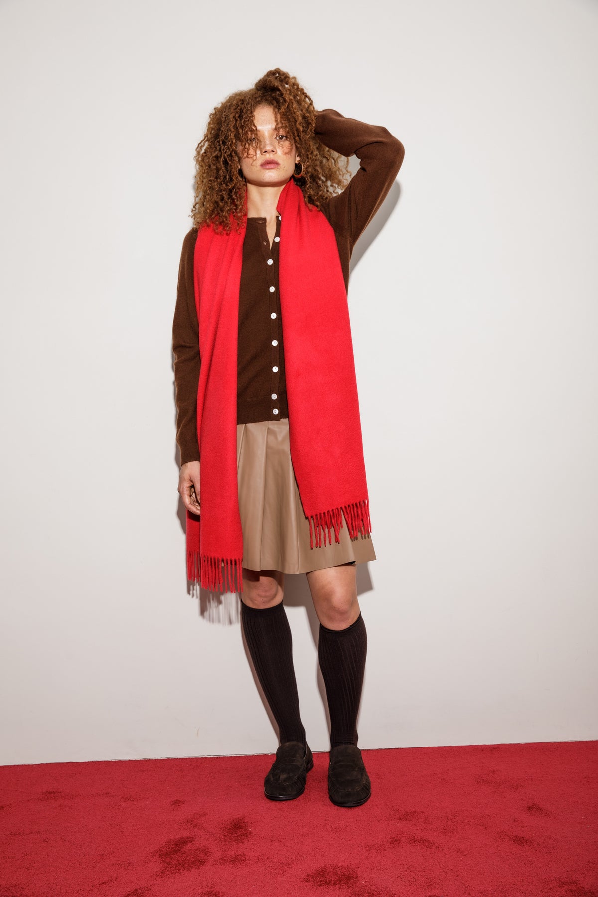 Solid Cashmere Wide Scarf in red styled draped over shoulders, showing fringed ends against a brown cardigan outfit