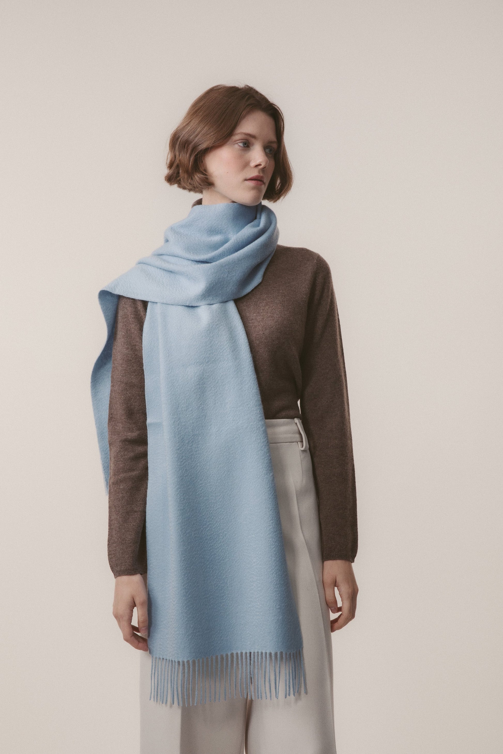 Solid Cashmere Wide Scarf in Blue styled on a model, draped around the neck with fringed ends visible
