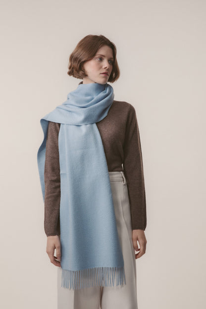 Solid Cashmere Wide Scarf in Blue styled on a model, draped around the neck with fringed ends visible