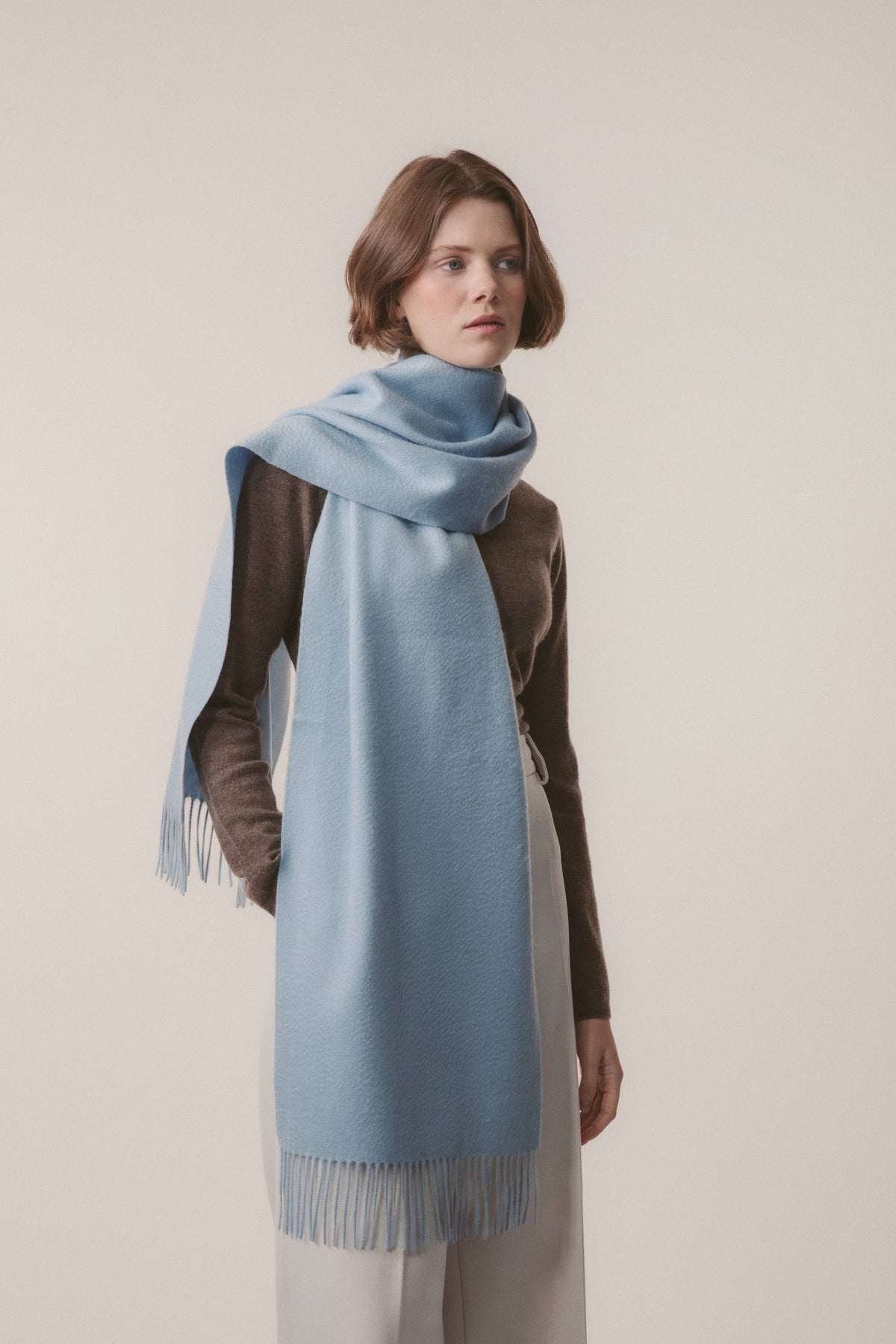 Solid Cashmere Wide Scarf in Blue styled wrapped around the neck with fringed ends draping to the front
