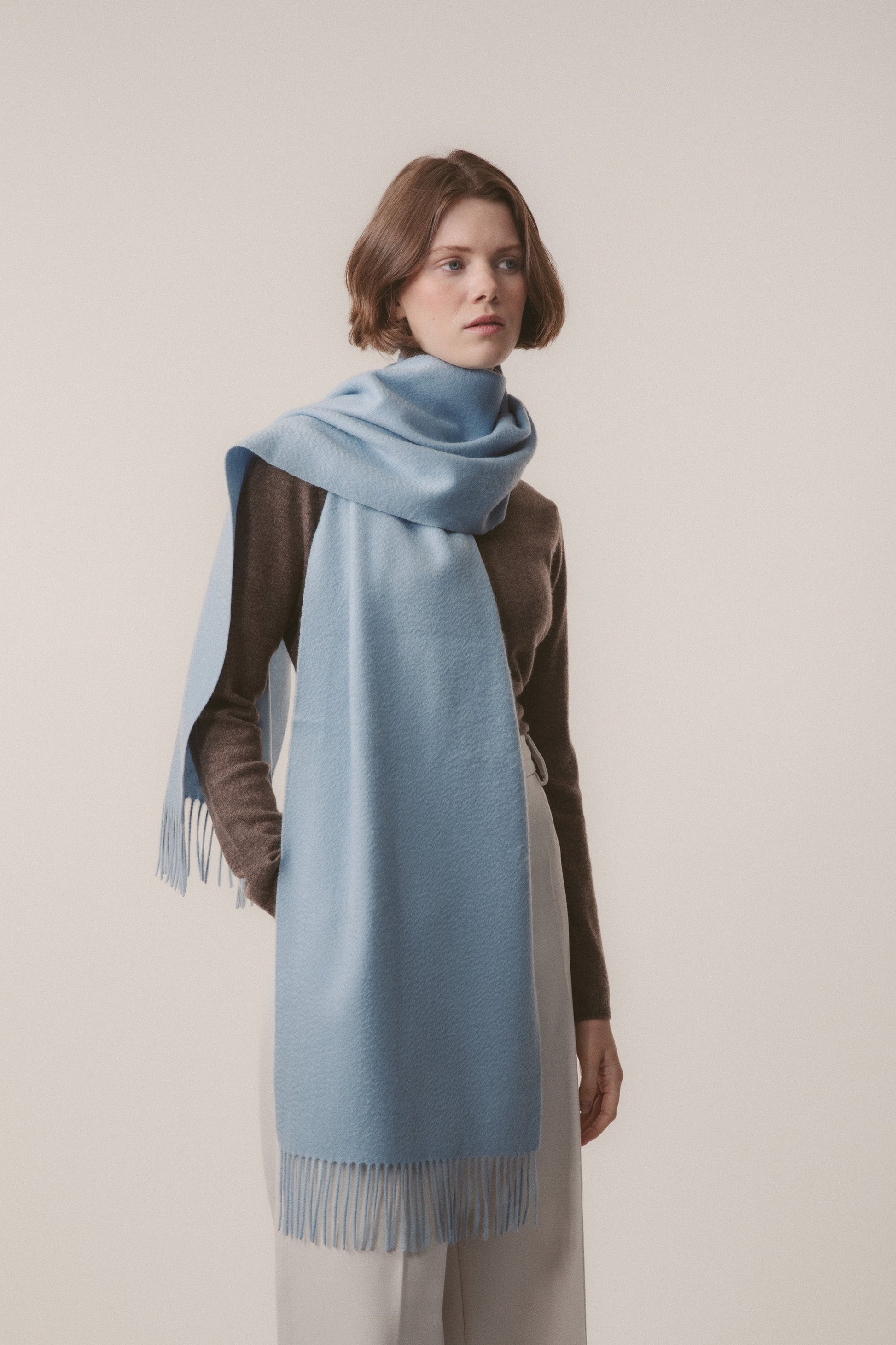 Solid Cashmere Wide Scarf in Blue styled wrapped around the neck with fringed ends draping to the front