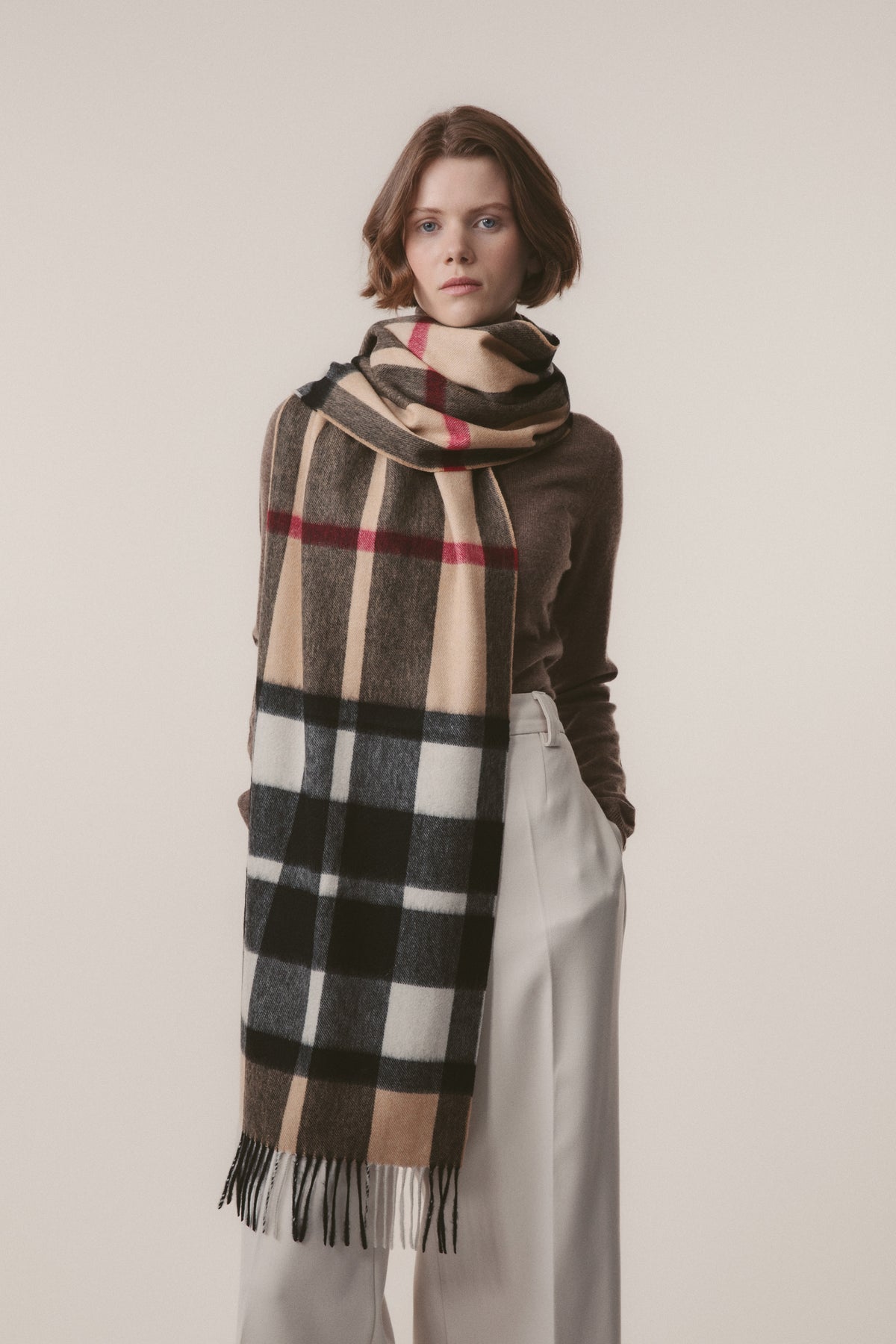 Model wearing Exploded Camel Thompson Cashmere Wide Scarf draped over one shoulder, showing full check pattern with fringed hem