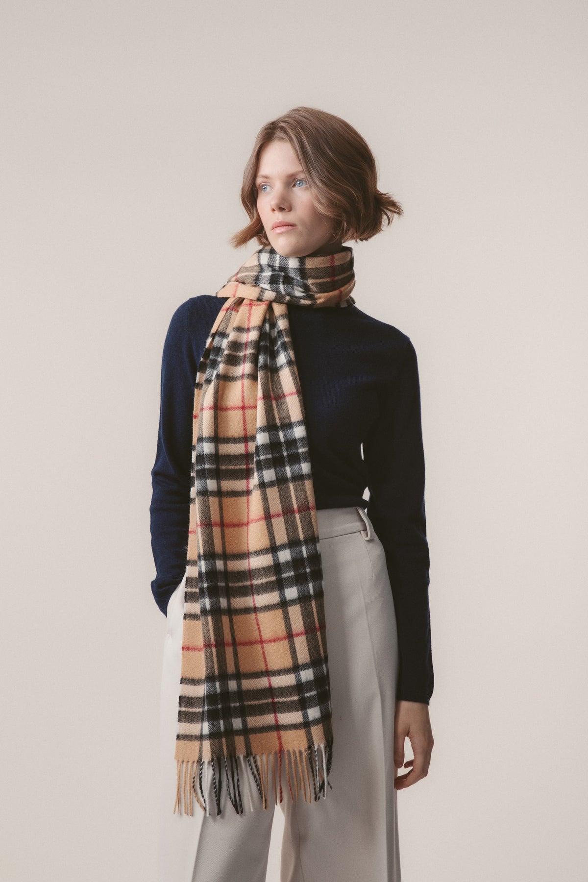 Scotty Thompson Cashmere Wide Scarf in Camel worn looped around the neck, showing the classic check pattern and fringed ends