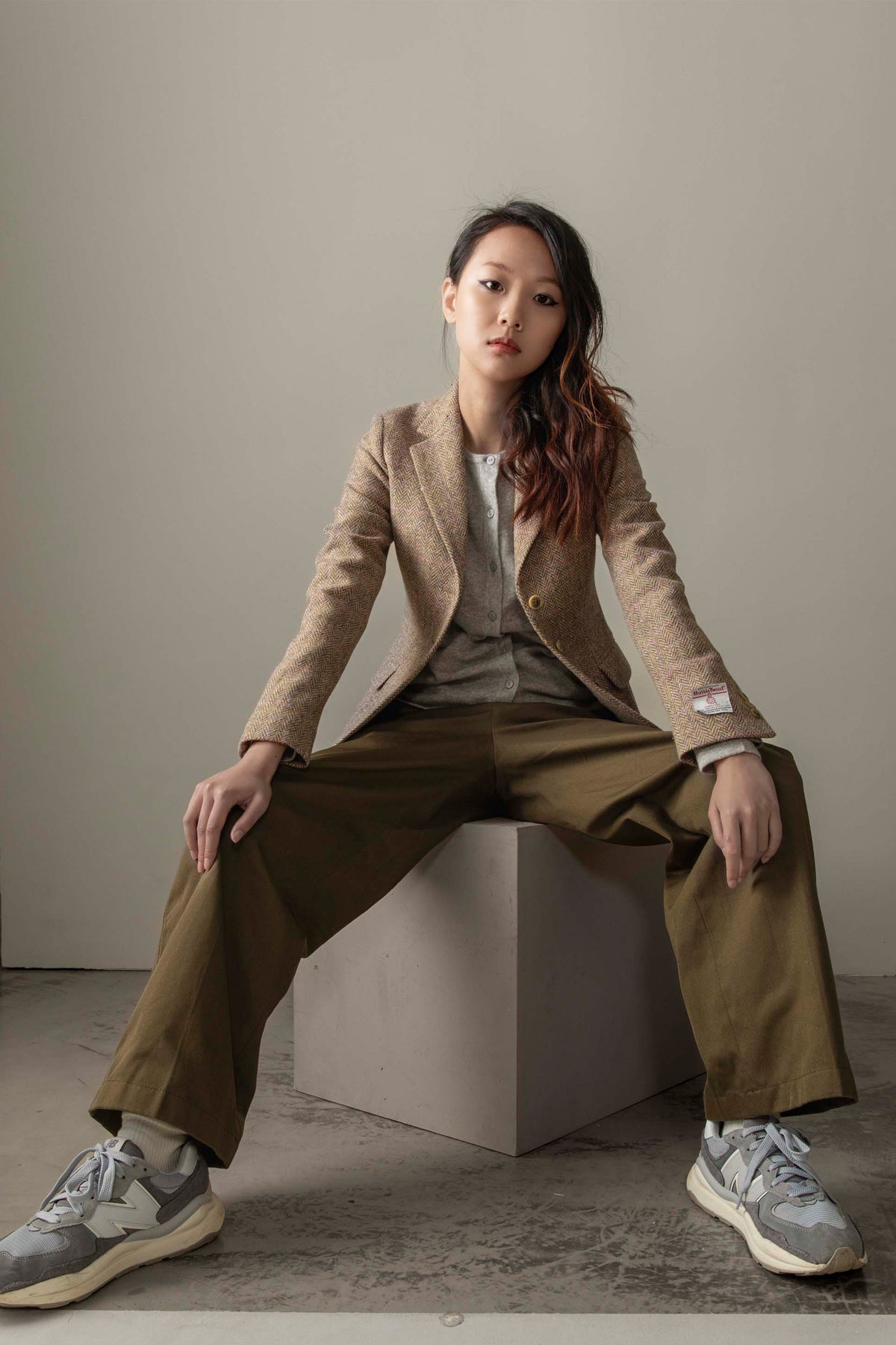 Women's Harris Tweed Claire Blazer in Beige Pink Windowpane styled seated with grey cardigan and olive wide-leg trousers