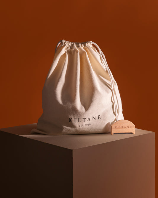 Kiltane Small Dustbag & Cashmere Comb — natural cotton drawstring bag with wooden comb beside it on a display plinth