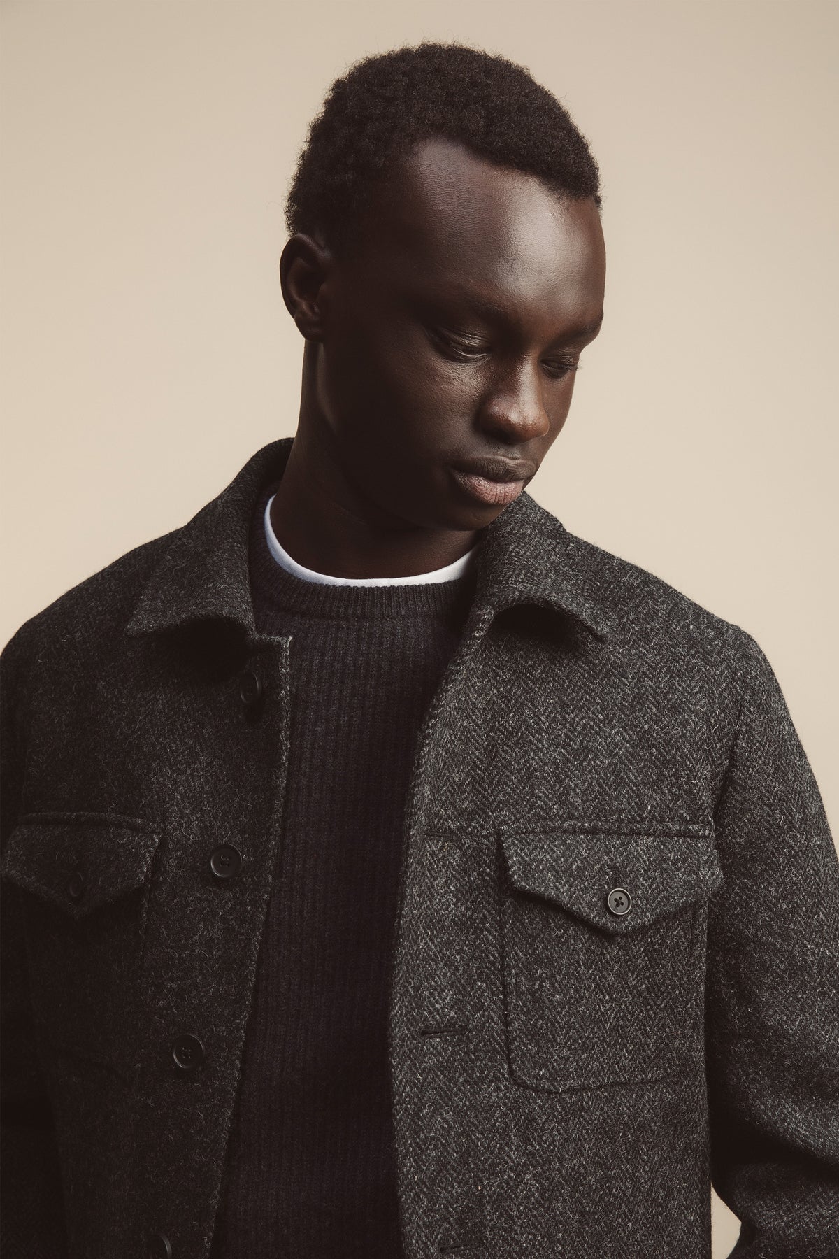 Close-up front view of Men's Harris Tweed Sergeant Jacket in Deep Charcoal showing herringbone weave, button-flap chest pockets, and collar detail