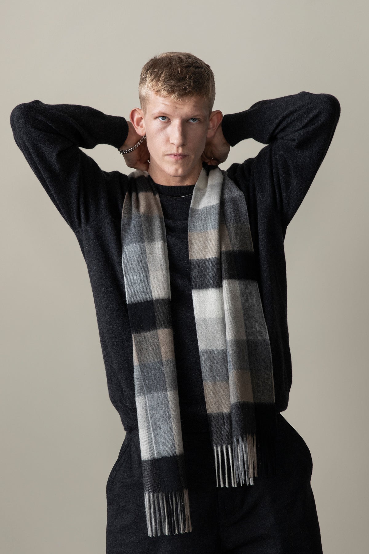 Model wearing 5 Square Check Cashmere Scarf in Black Grey draped over a dark sweater, showing the full check pattern and fringe detail