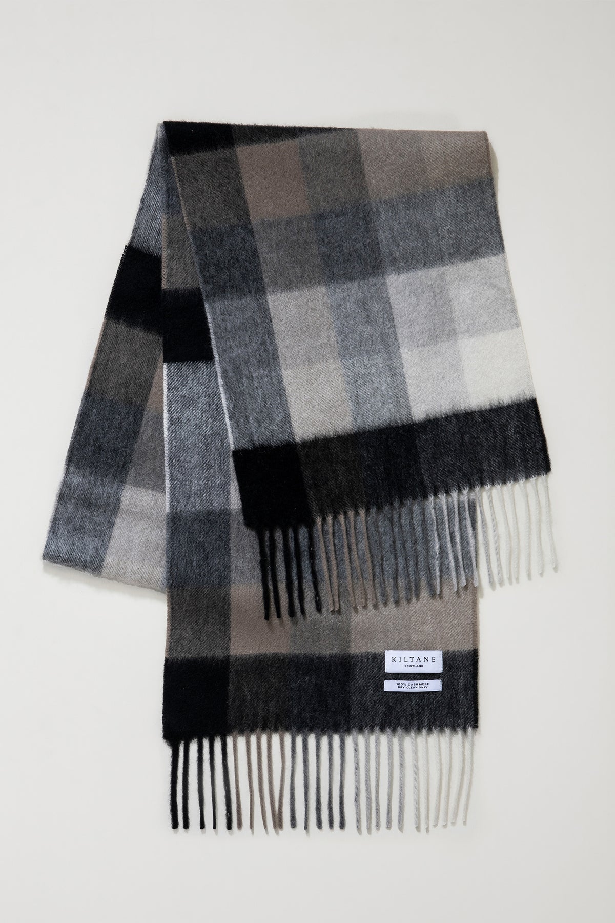 Kiltane Scotland label and fringed ends of the 5 Square Check Cashmere Scarf in black and grey, showing 100% cashmere tag