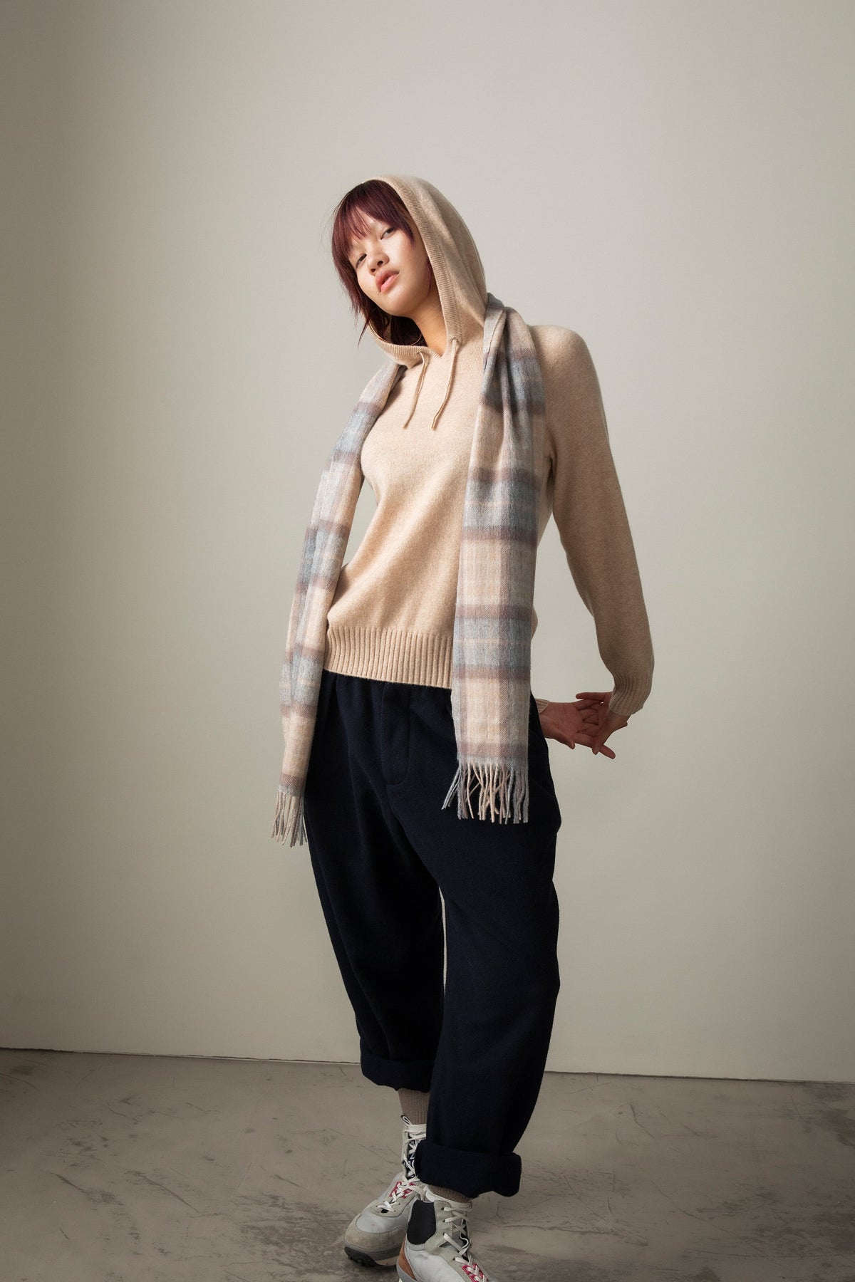 Heritage Tartan Cashmere Scarf in Mackellar Natural worn as a hood, featuring soft beige, grey, and pink plaid with fringed ends