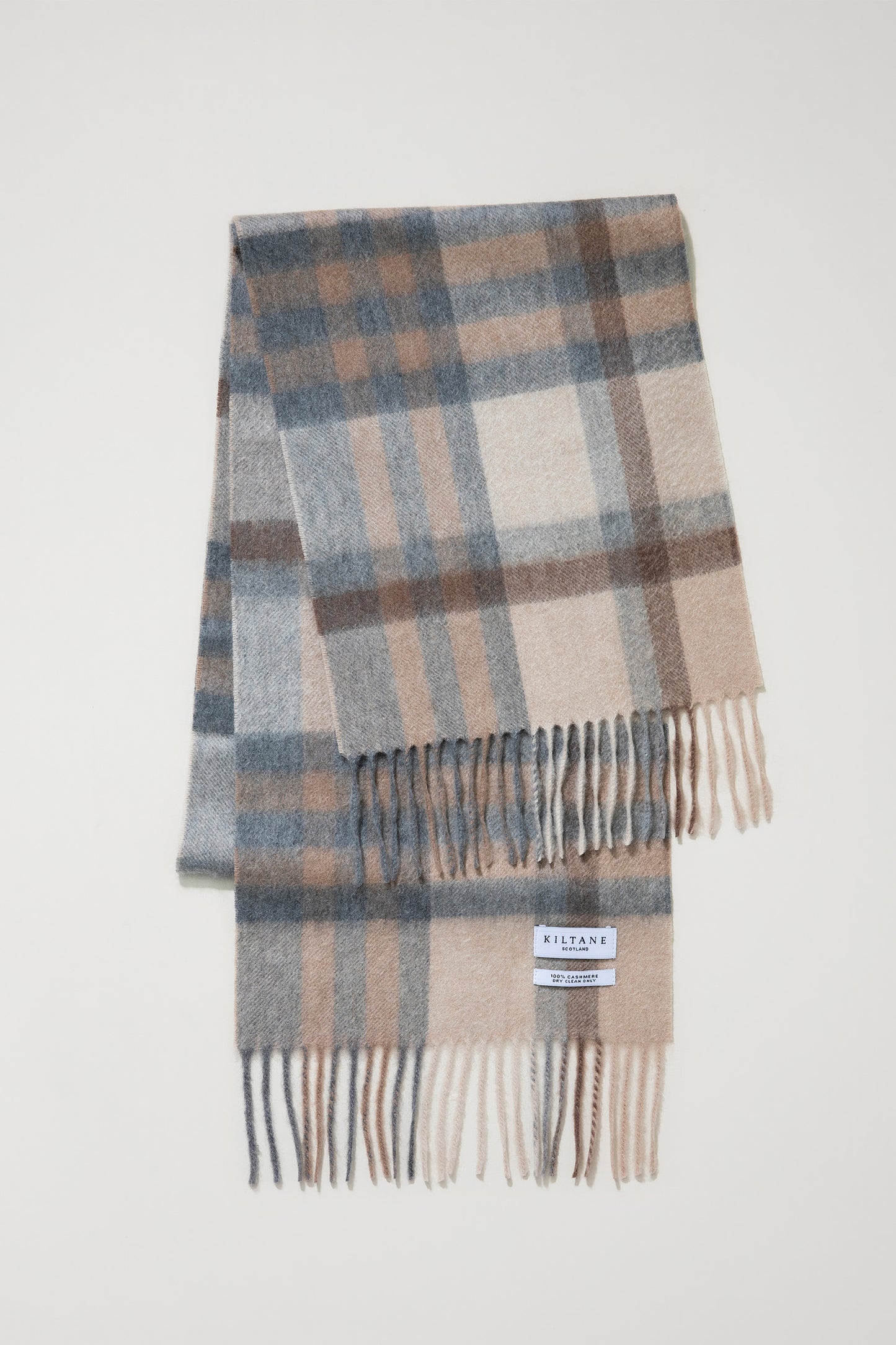 Made In Scotland Tartan 2 Cashmere Scarf in Natural, folded flat showing soft plaid pattern in beige, grey, and cream with fringed ends