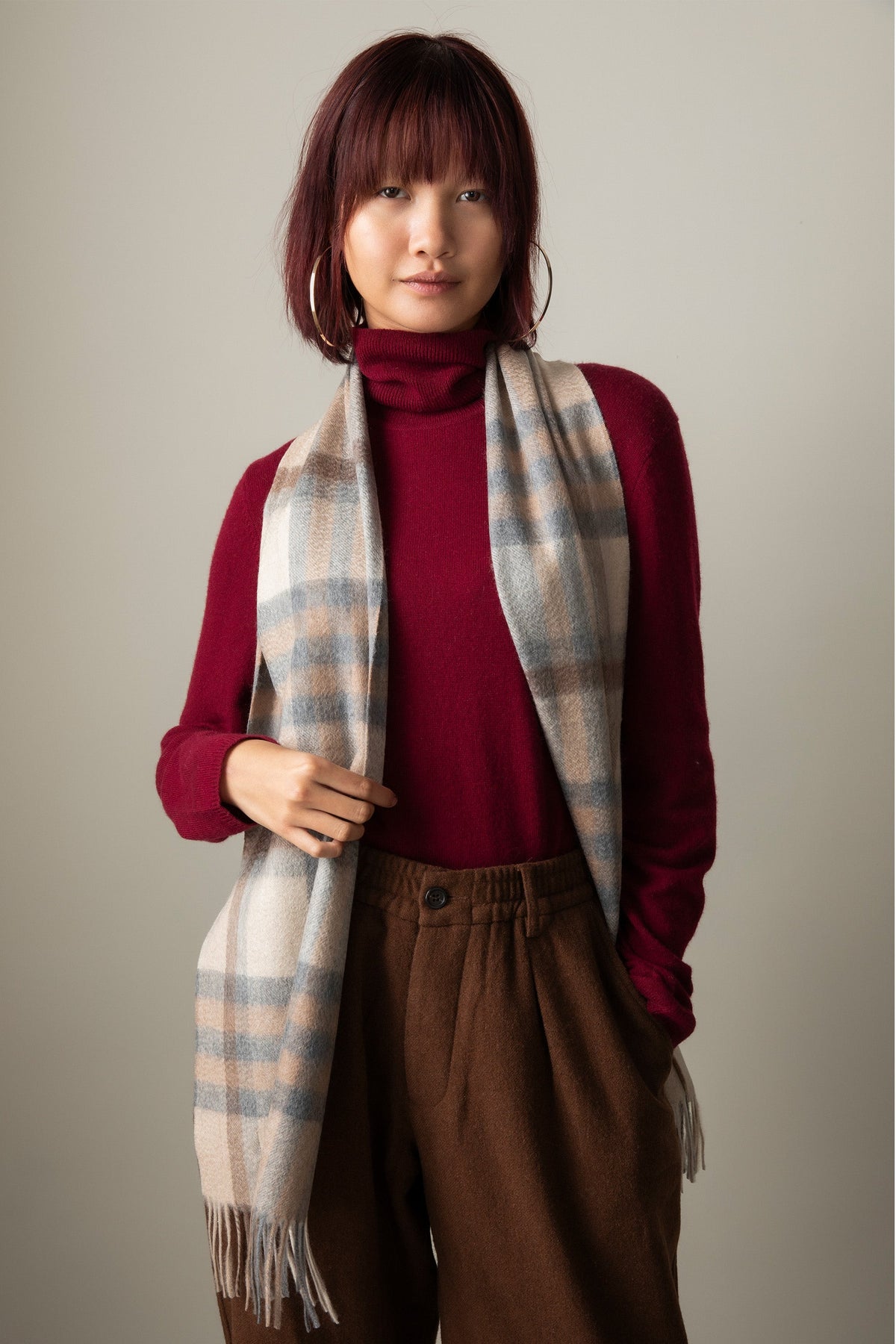 Tartan 2 Cashmere Scarf in Natural, soft plaid pattern in cream, beige and blue tones with fringed ends, styled over a burgundy turtleneck