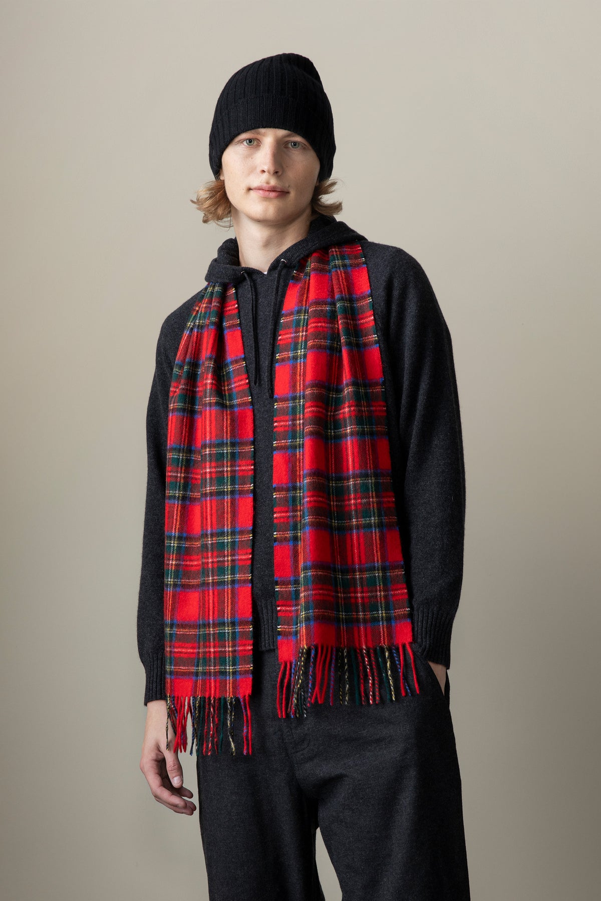 Heritage Tartan Cashmere Scarf in Official Royal Stewart red tartan with fringed ends, worn draped over a dark hoodie