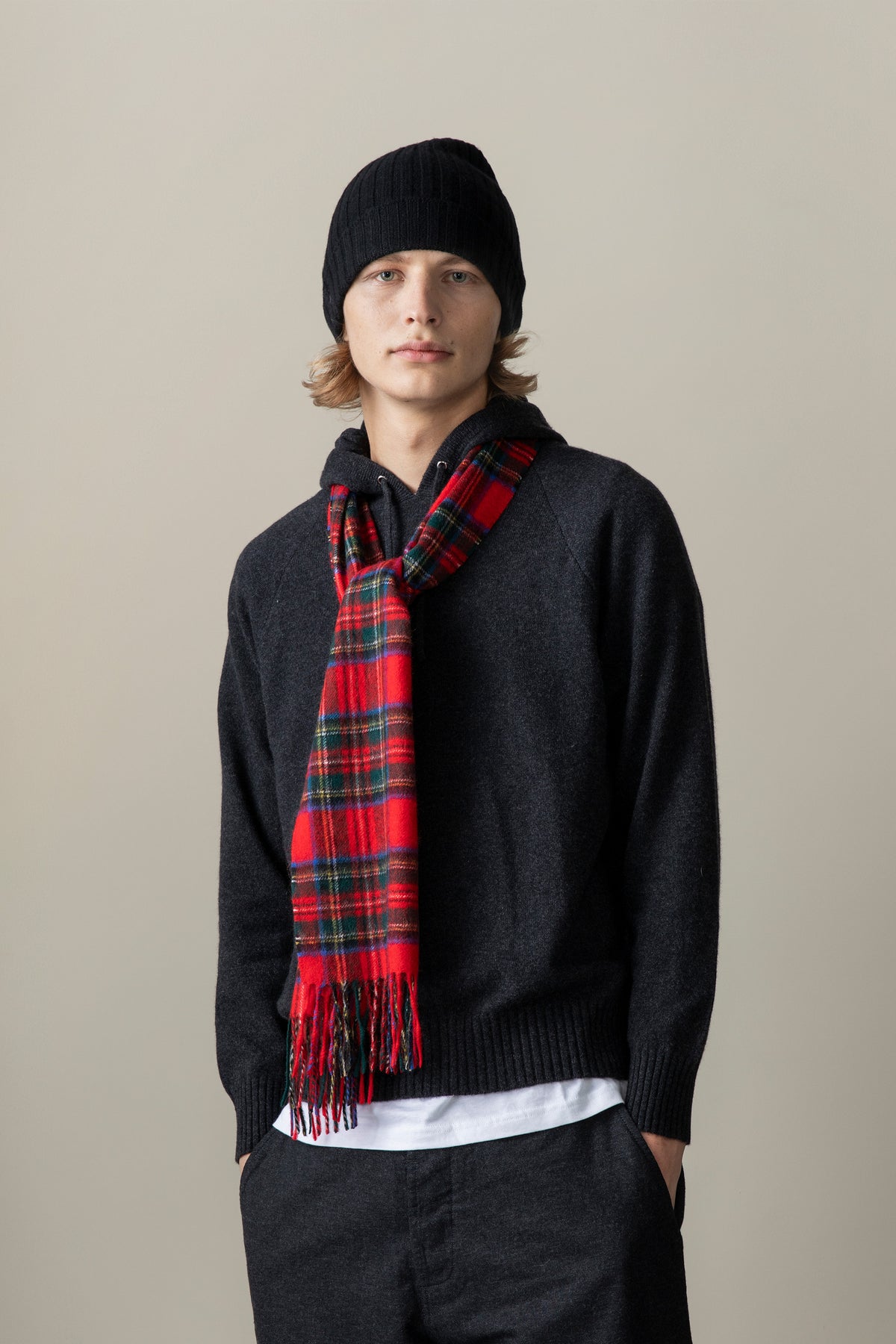 Heritage Tartan Cashmere Scarf in Royal Stewart worn loosely draped over a dark hoodie, showing fringe detail