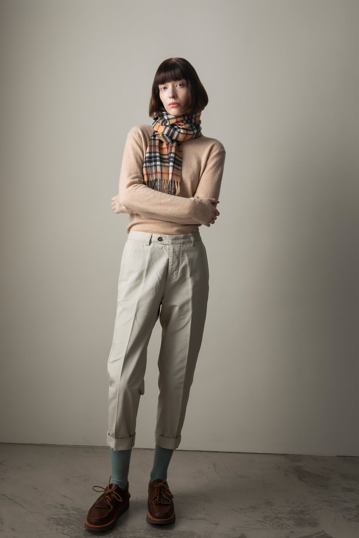 Scotty Thompson Cashmere Scarf in Camel plaid worn knotted around the neck, styled with a beige sweater and cream trousers