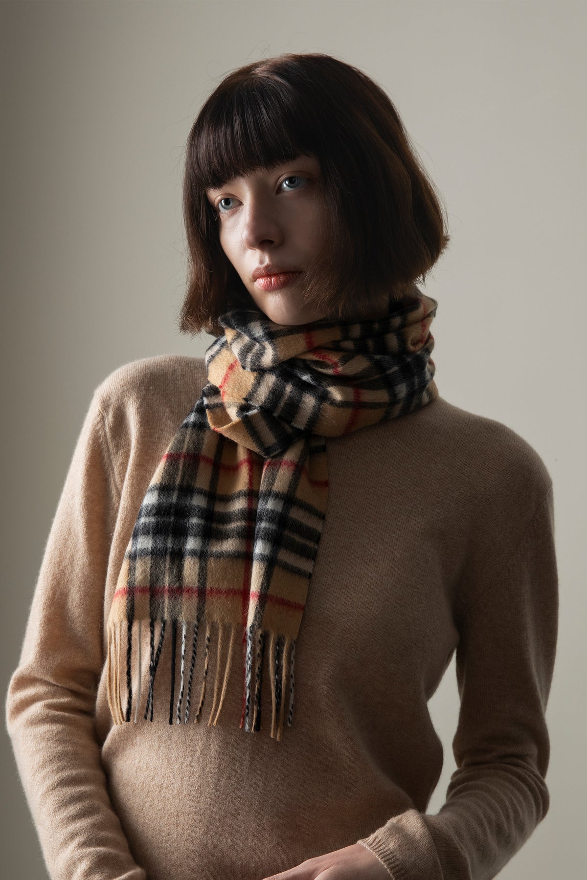 Scotty Thompson Cashmere Scarf in Camel worn wrapped around the neck, showing classic check pattern with fringed ends