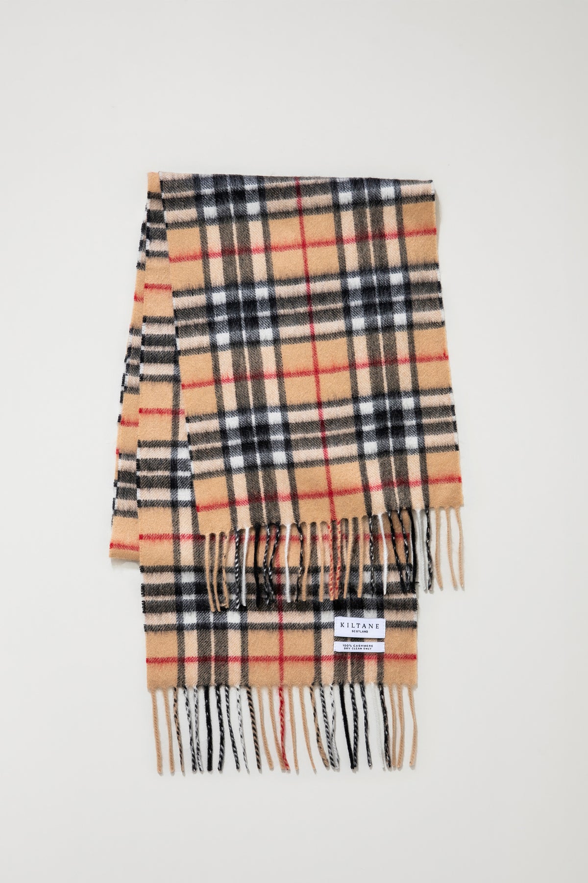 Kiltane Scotland label and fringe detail on Scotty Thompson Cashmere Scarf in camel tartan with black, white, and red plaid