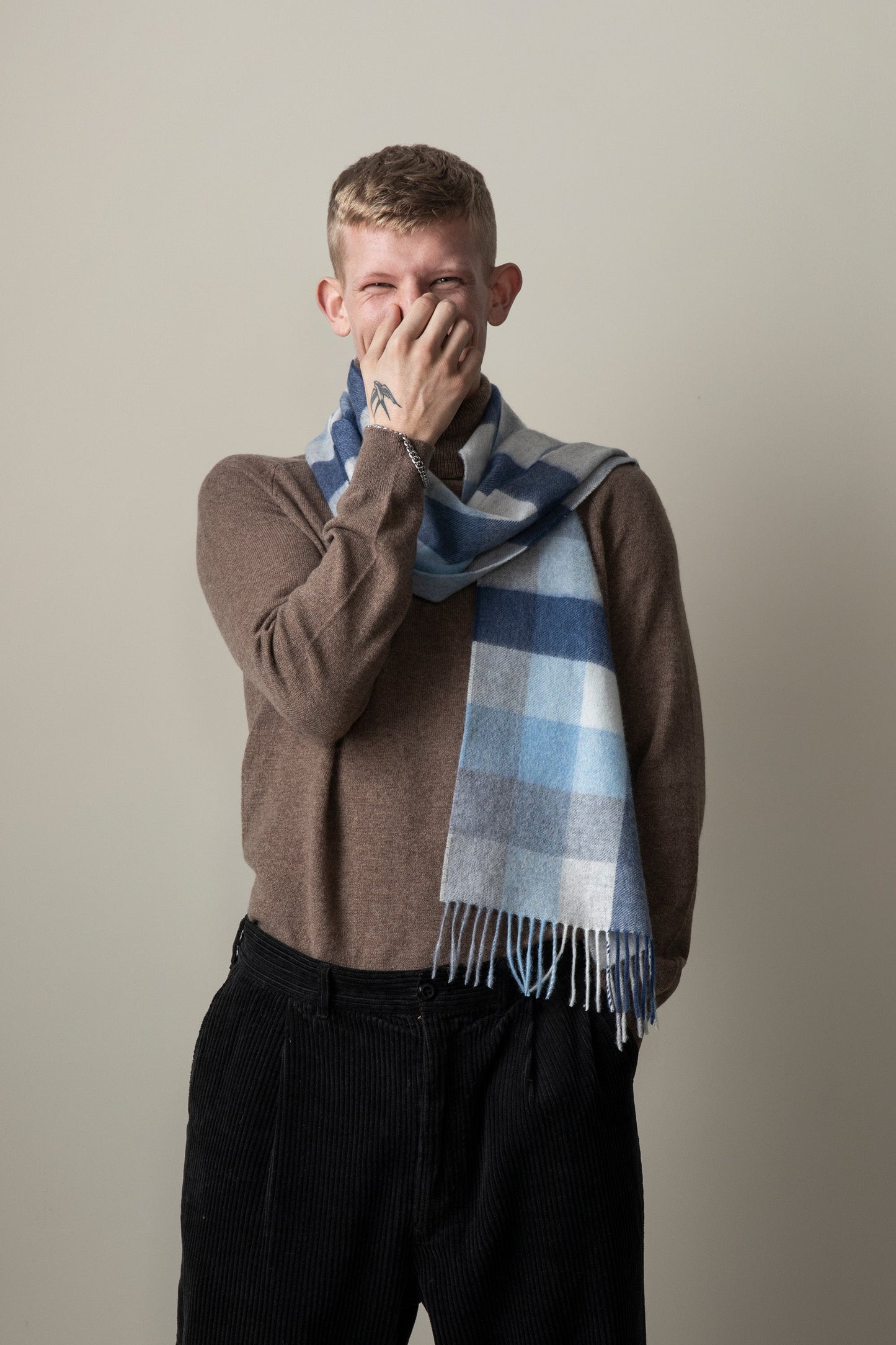 5 Square Check Cashmere Scarf in Glacier worn loosely around the neck by a model, showing blue check pattern and fringed ends