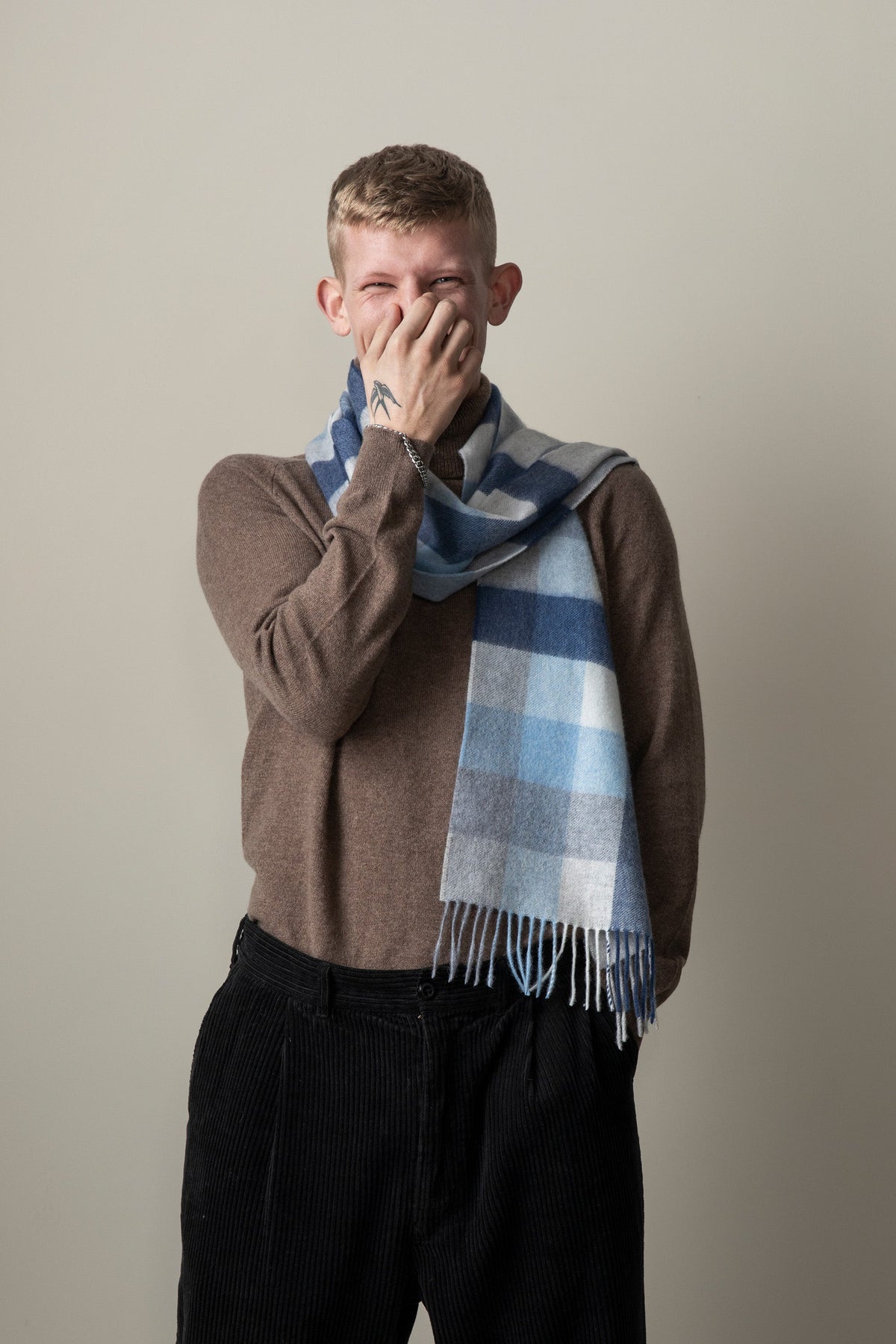 5 Square Check Cashmere Scarf in Glacier worn loosely around the neck by a model, showing blue check pattern and fringed ends