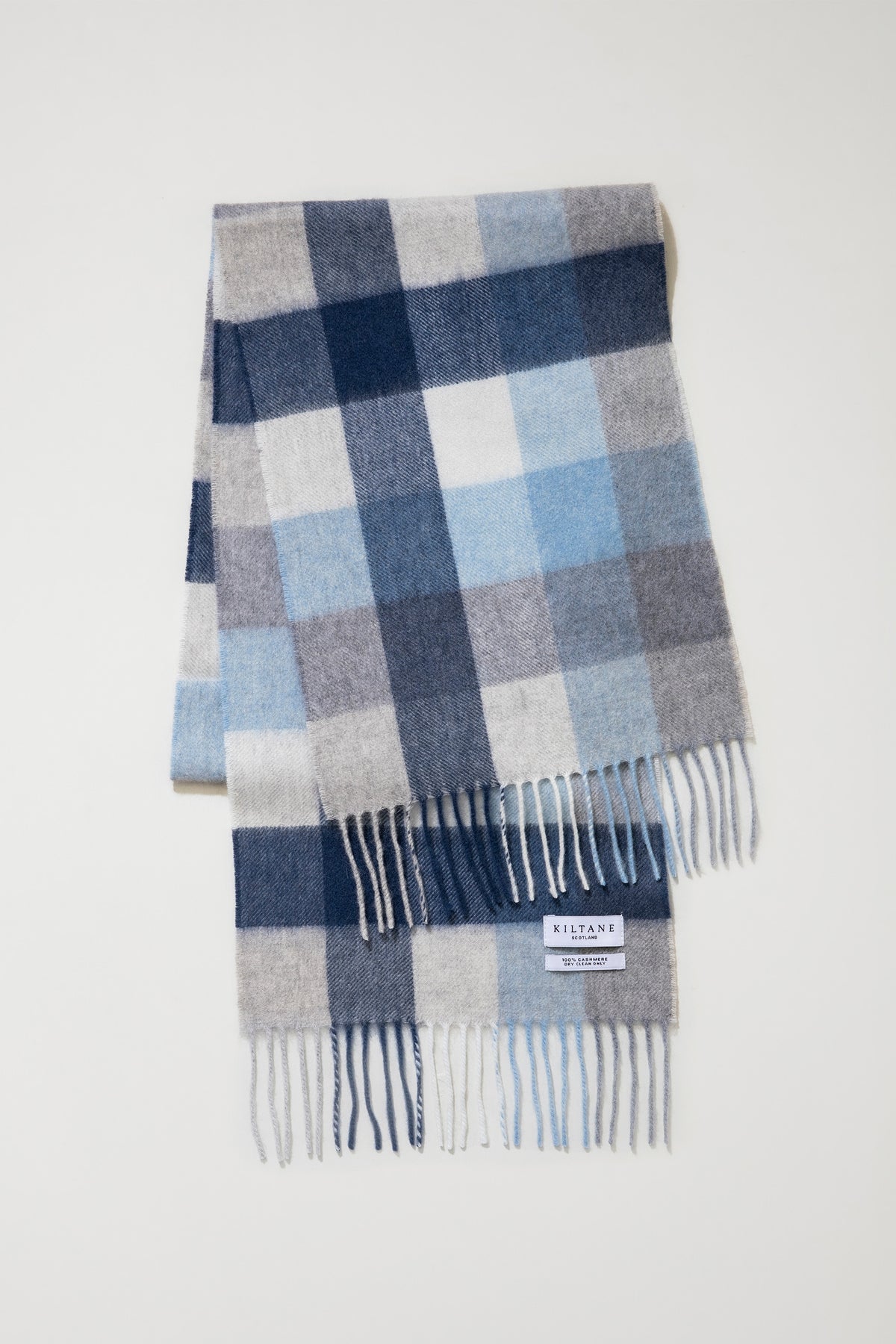 5 Square Check Cashmere Scarf - Glacier folded flat showing blue, navy, grey, and white check pattern with fringed ends