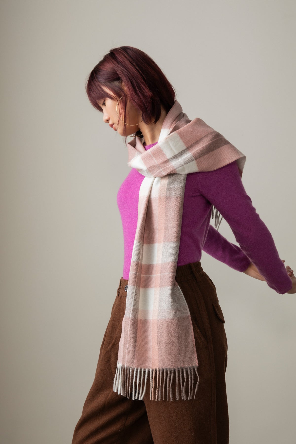 Contemporary Check Cashmere Scarf - Cameo worn draped over the shoulder, showing pink and cream check pattern with fringed ends