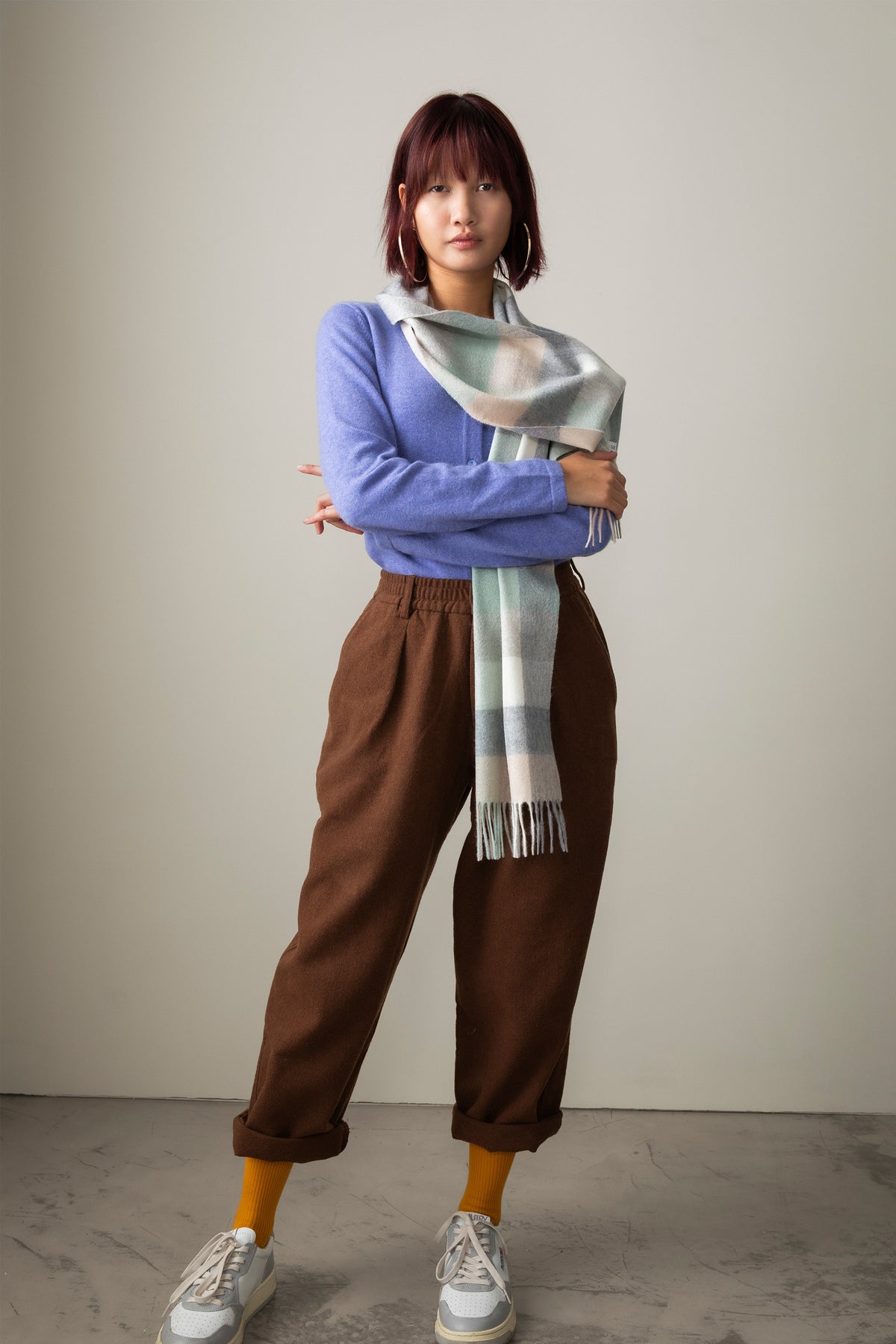 5 Square Check Cashmere Scarf in Brume styled draped over shoulders with fringed ends visible, paired with a lavender sweater