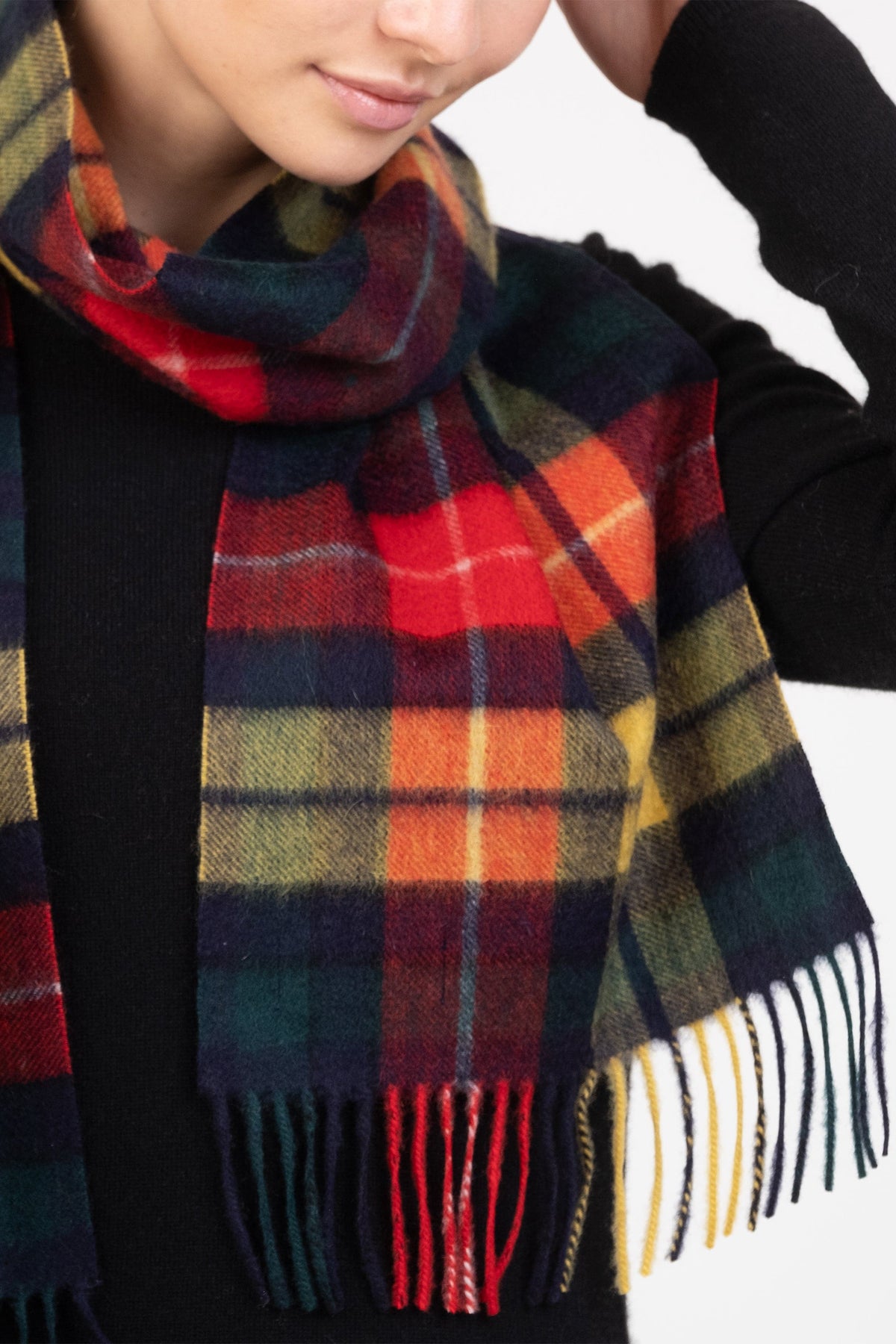Heritage Tartan Cashmere Scarf in Buchanan Modern worn loosely over a black sweater, showing fringe detail and vibrant plaid pattern