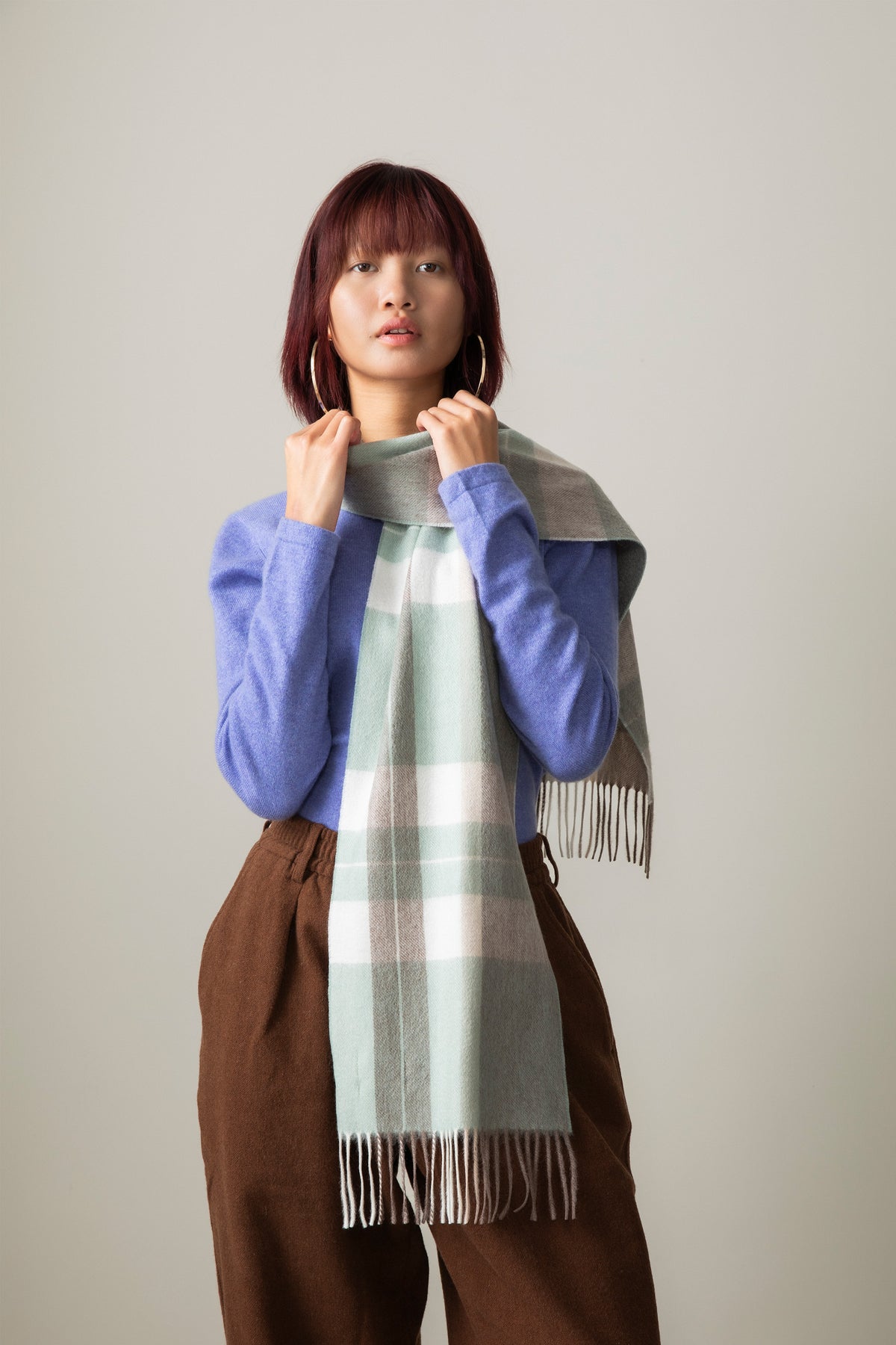 Model wearing Contemporary Check Cashmere Scarf in Seafoam draped over shoulders, showing plaid pattern with fringed ends