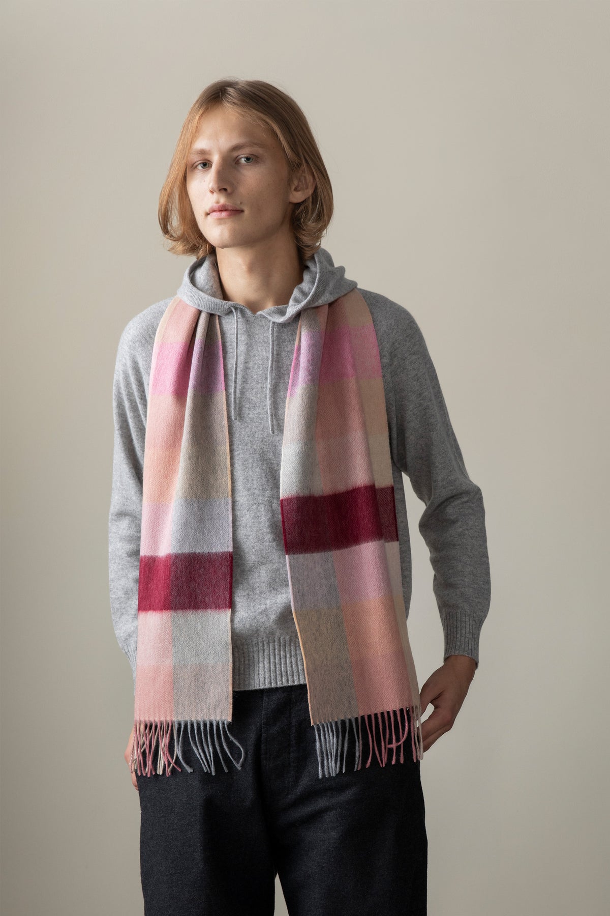 3 Square Cashmere Scarf in Summer Fruits worn draped over a grey hoodie, featuring pink, beige, grey, and burgundy check pattern with fringed ends