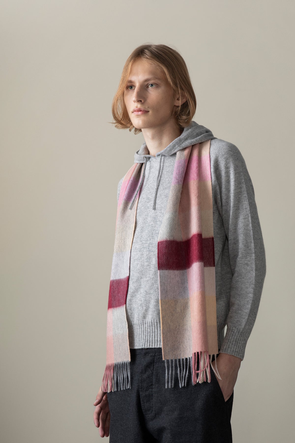 3 Square Cashmere Scarf in Summer Fruits worn draped over a grey hoodie, showing pink, burgundy, and beige check pattern with fringe